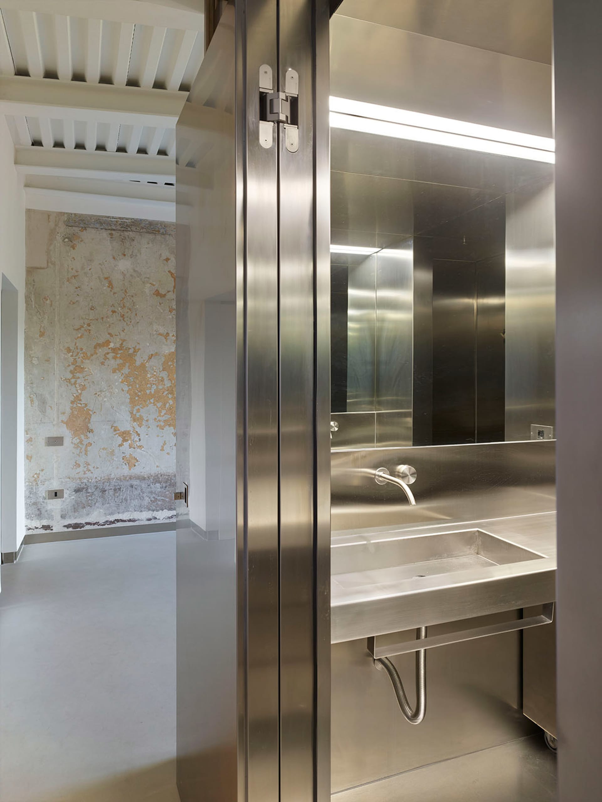 A modern, minimalist bathroom featuring stainless steel surfaces and fixtures.