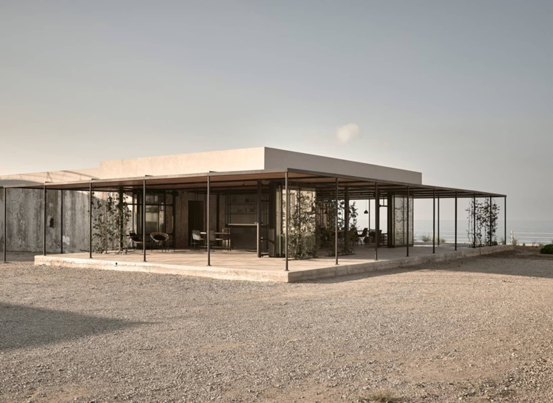 Modern minimalist residential exterior featuring exposed concrete structure and minimalist design elements.