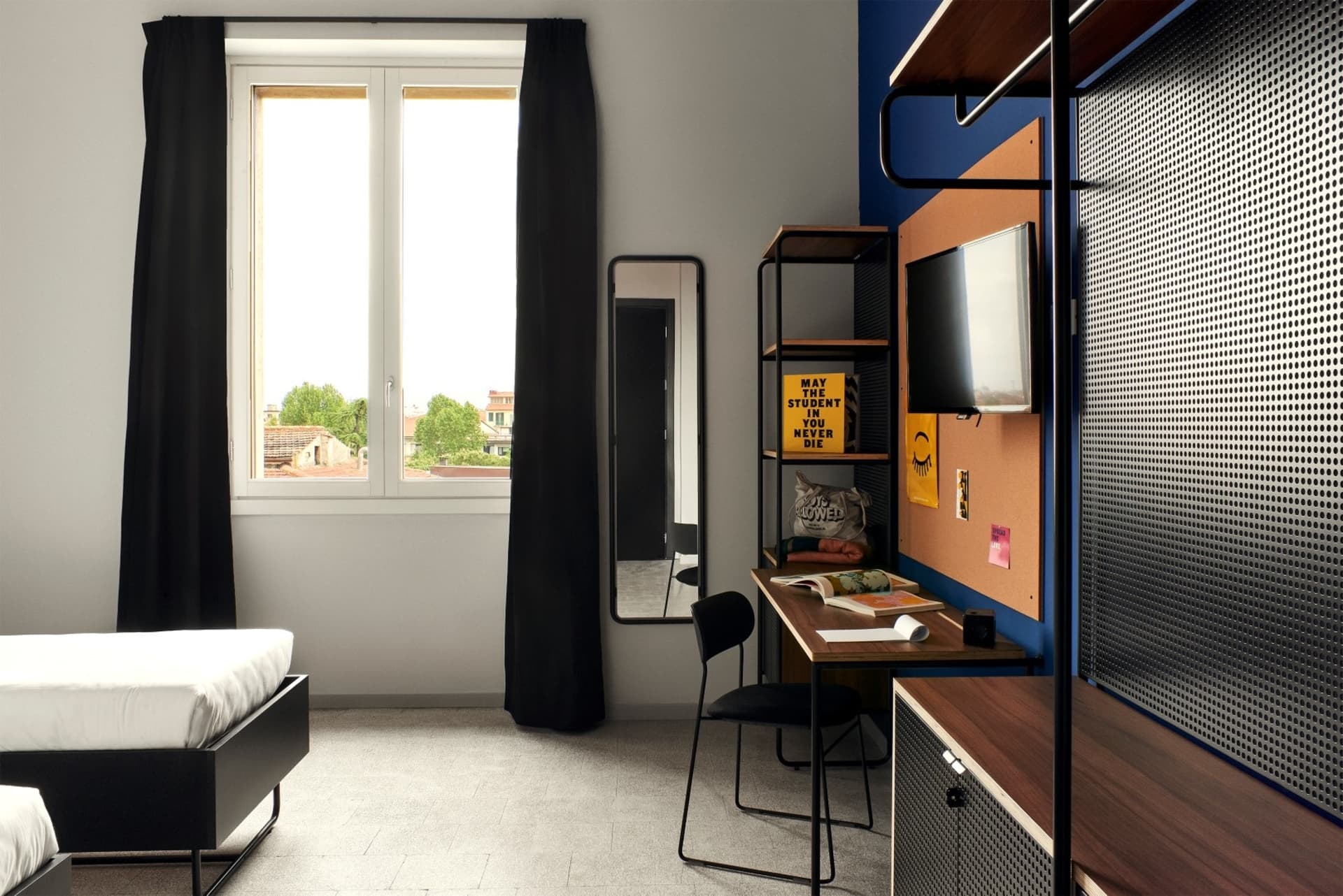Contemporary bedroom interior with metal frame bed, wooden desk, and fabric chair.