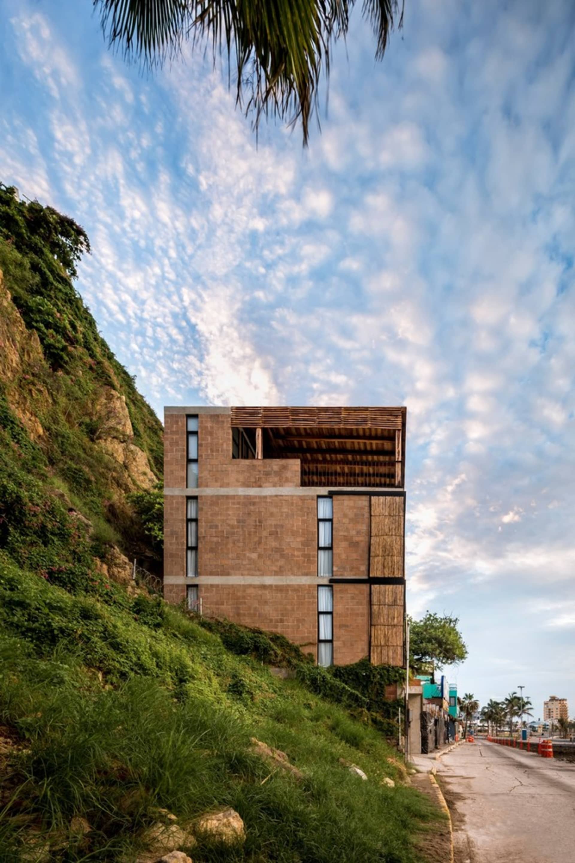 A modern building constructed of concrete, situated on a grassy hillside with a blue sky in the background.