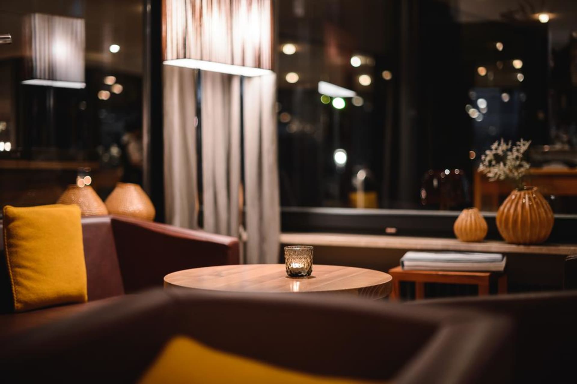 Modern living space with a wooden table and a single toasted candle.