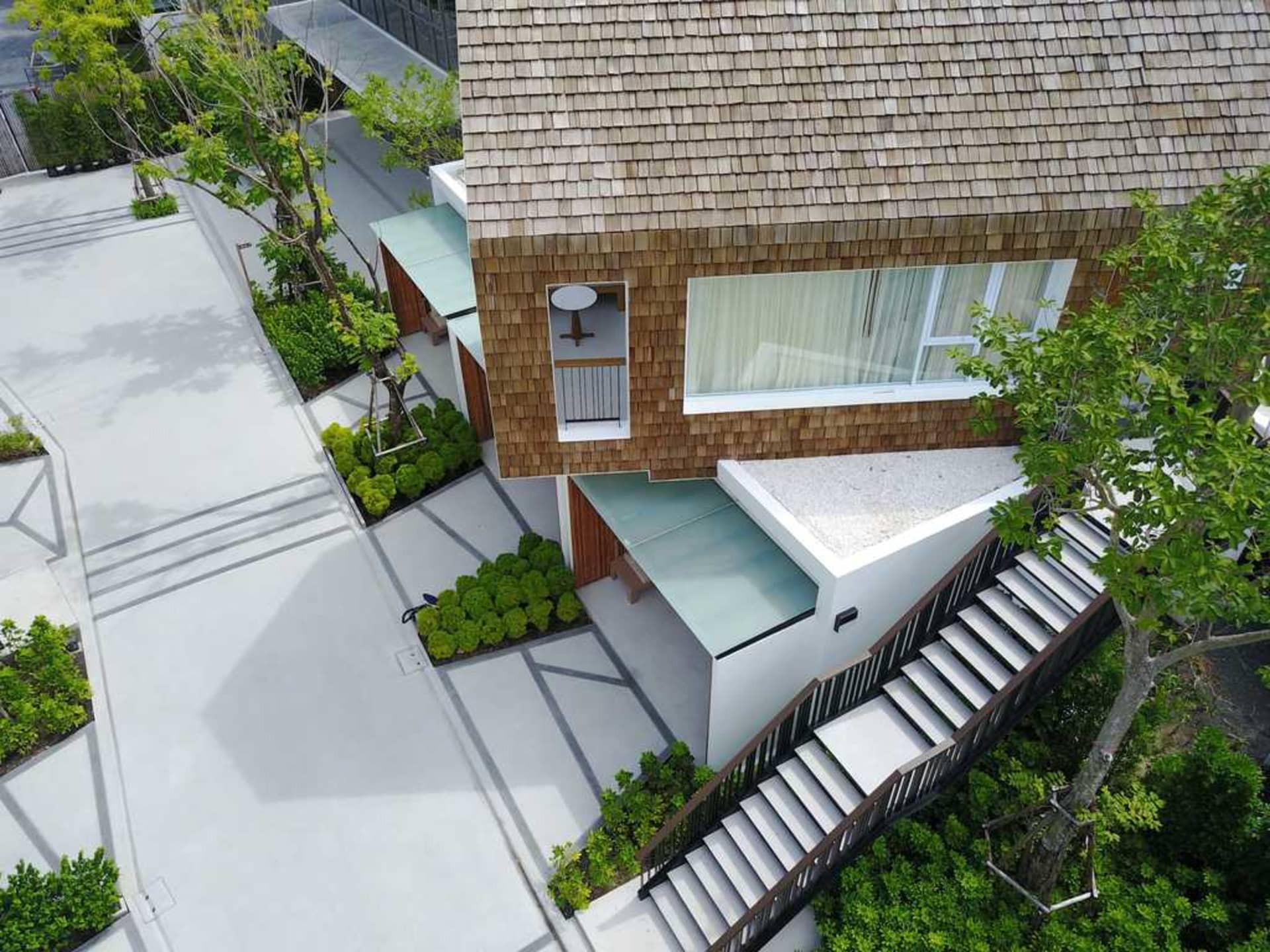 Aerial view of a modern house with wood-shingles and a concrete pathway.