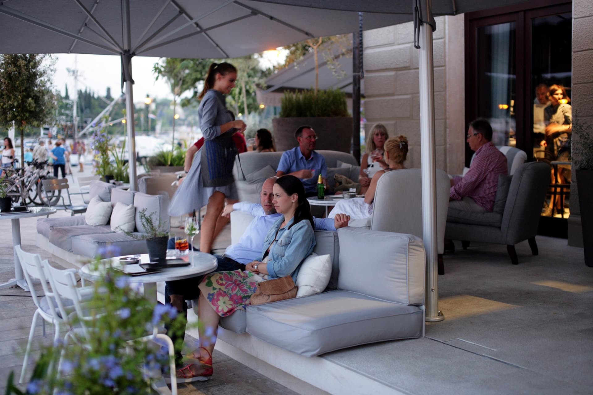 An outdoor seating area of a restaurant with fabric furniture and urban surroundings.