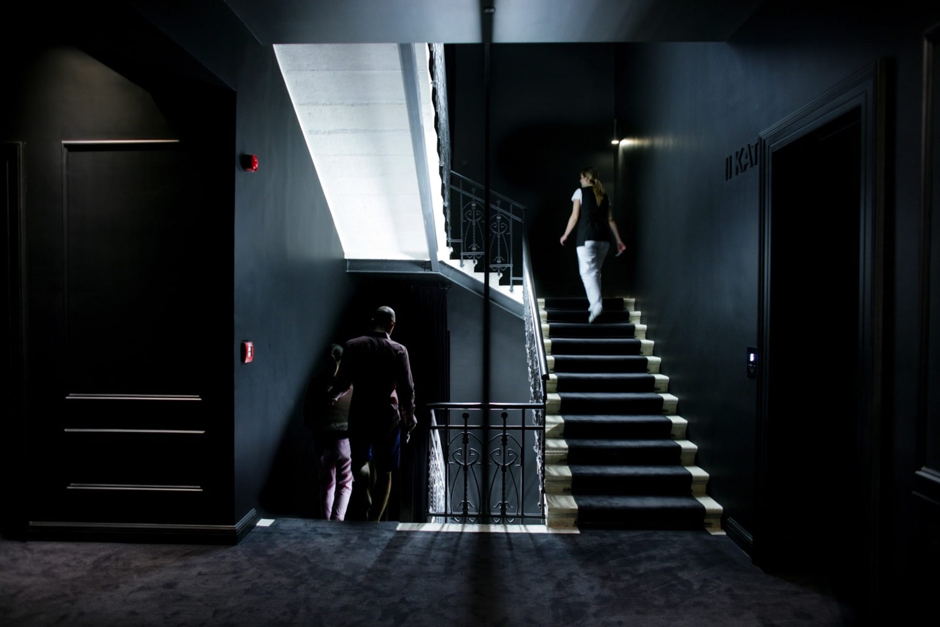 A modern hotel staircase with metal railings and black walls.