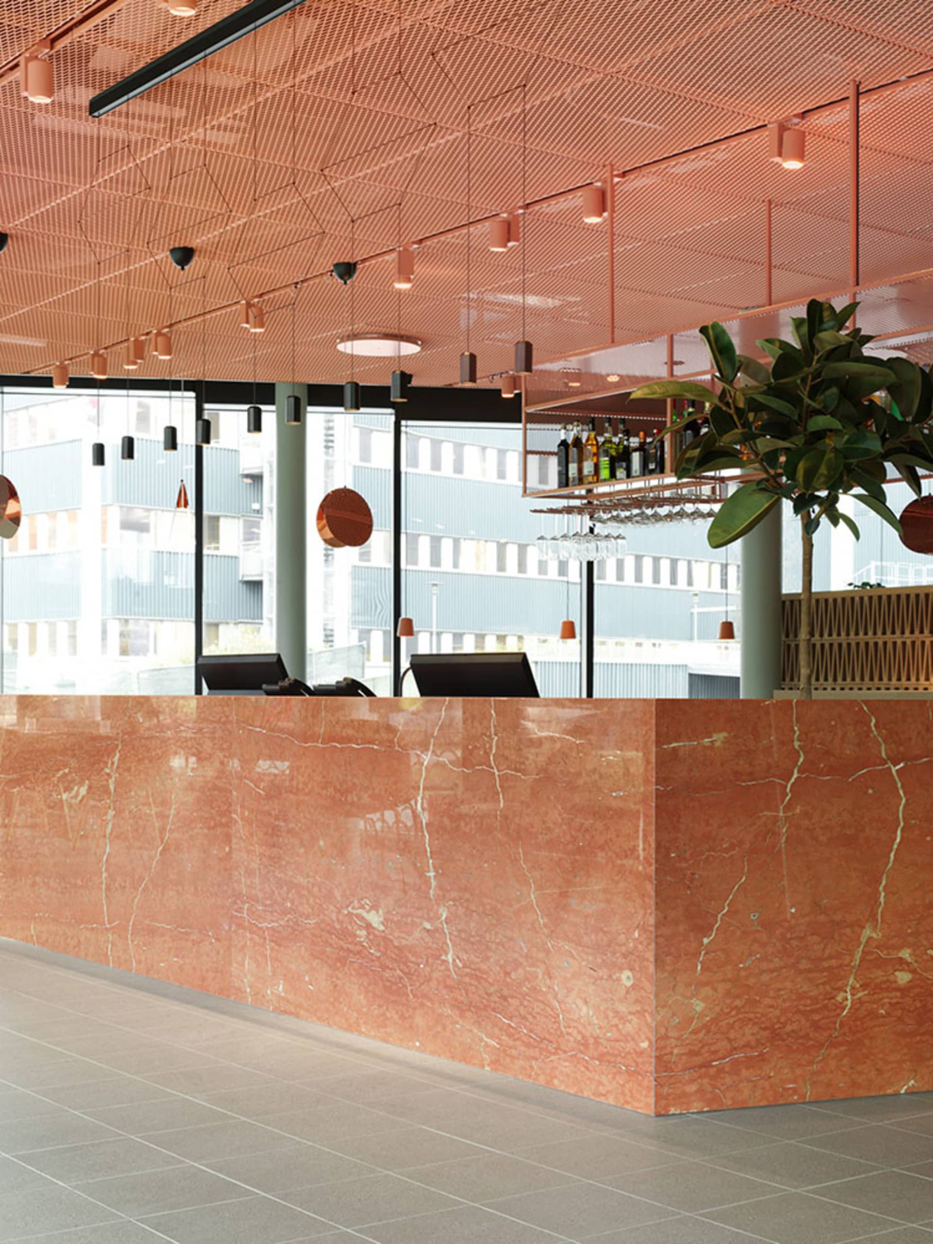 Modern restaurant interior featuring a polished marble counter with seating and decorative elements.