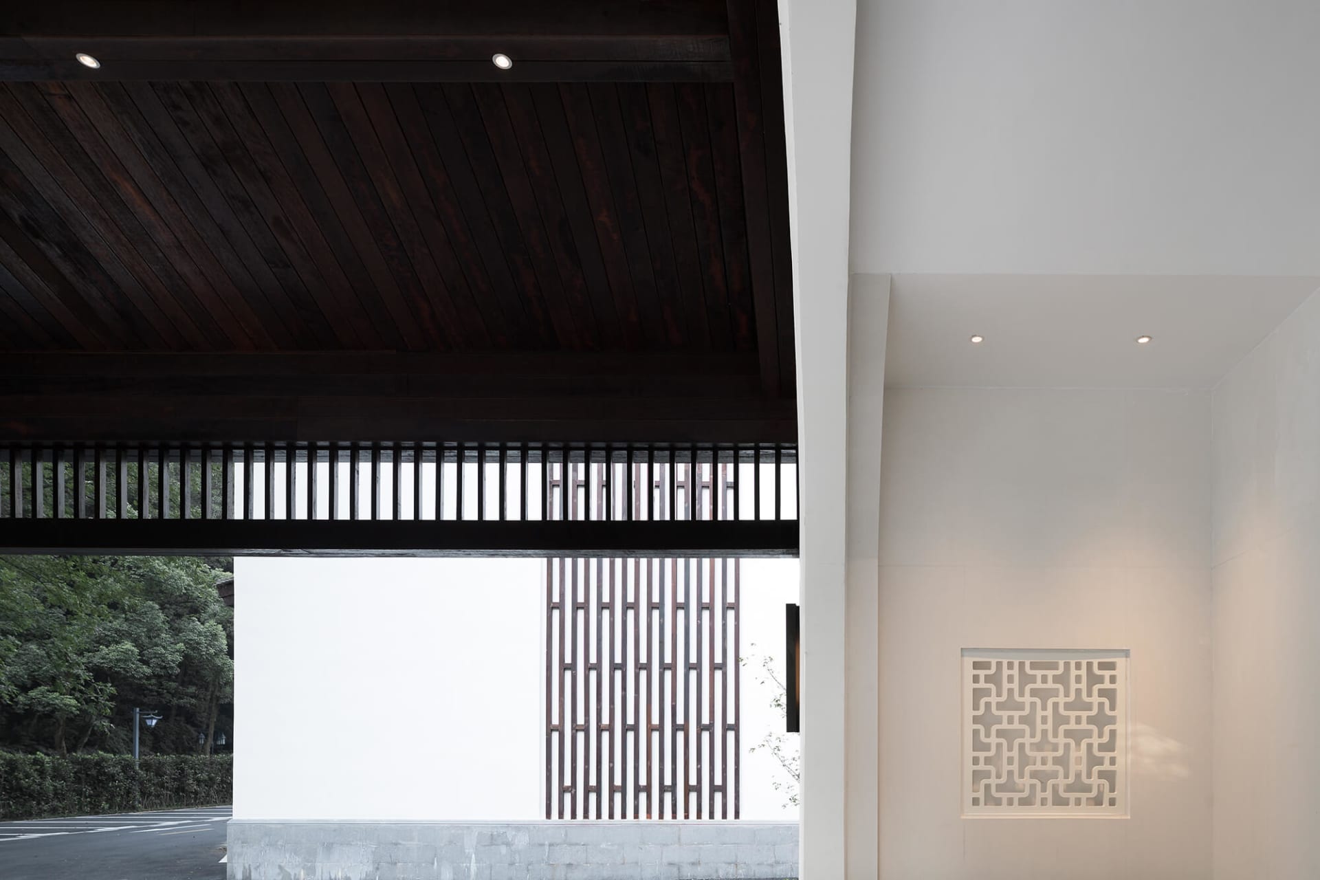 A minimalist entryway featuring wooden cabinets with geometric patterns, concrete walls, and paper lanterns.