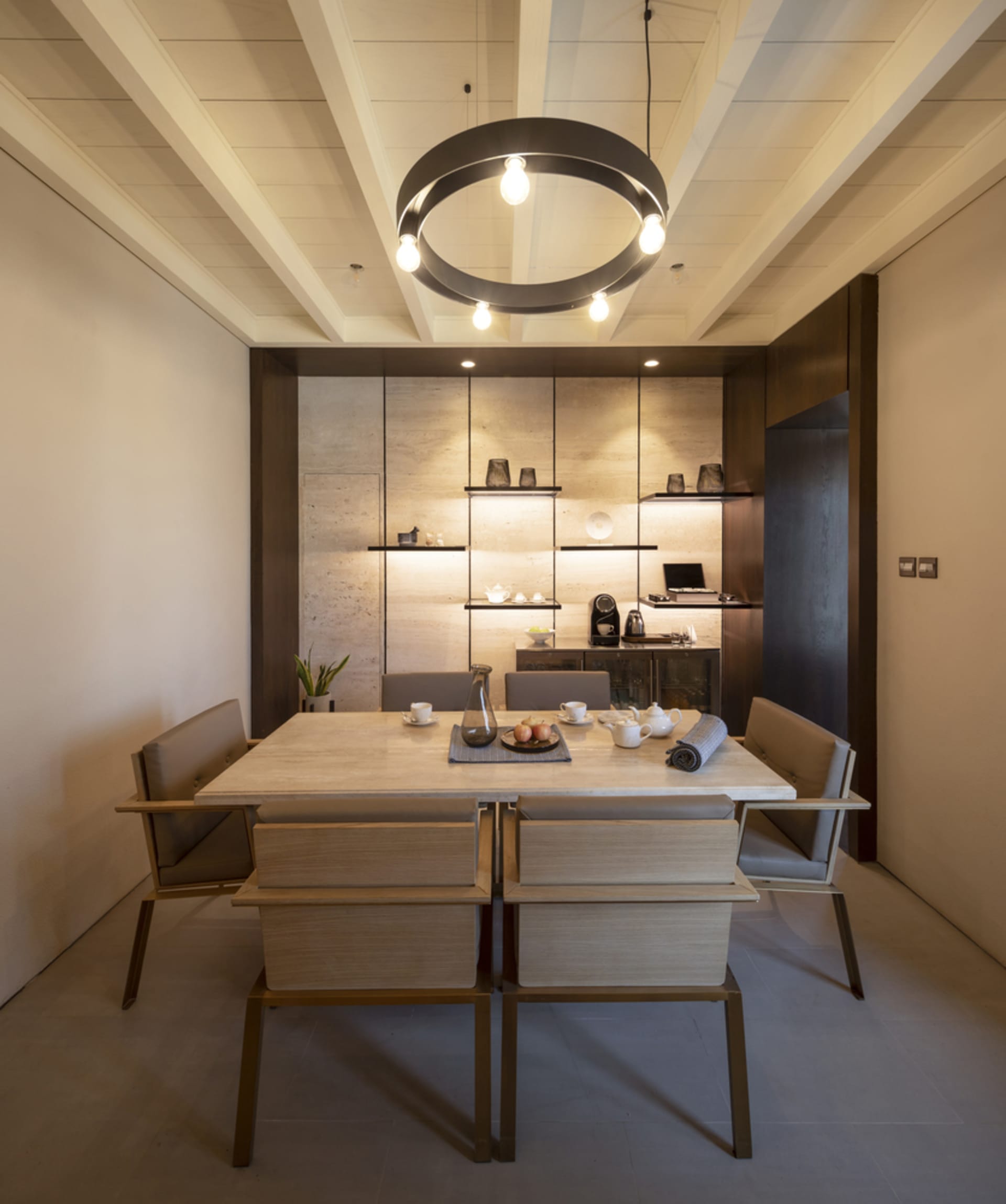 A modern dining room with a stone table and chairs, minimalistic design, and warm lighting.