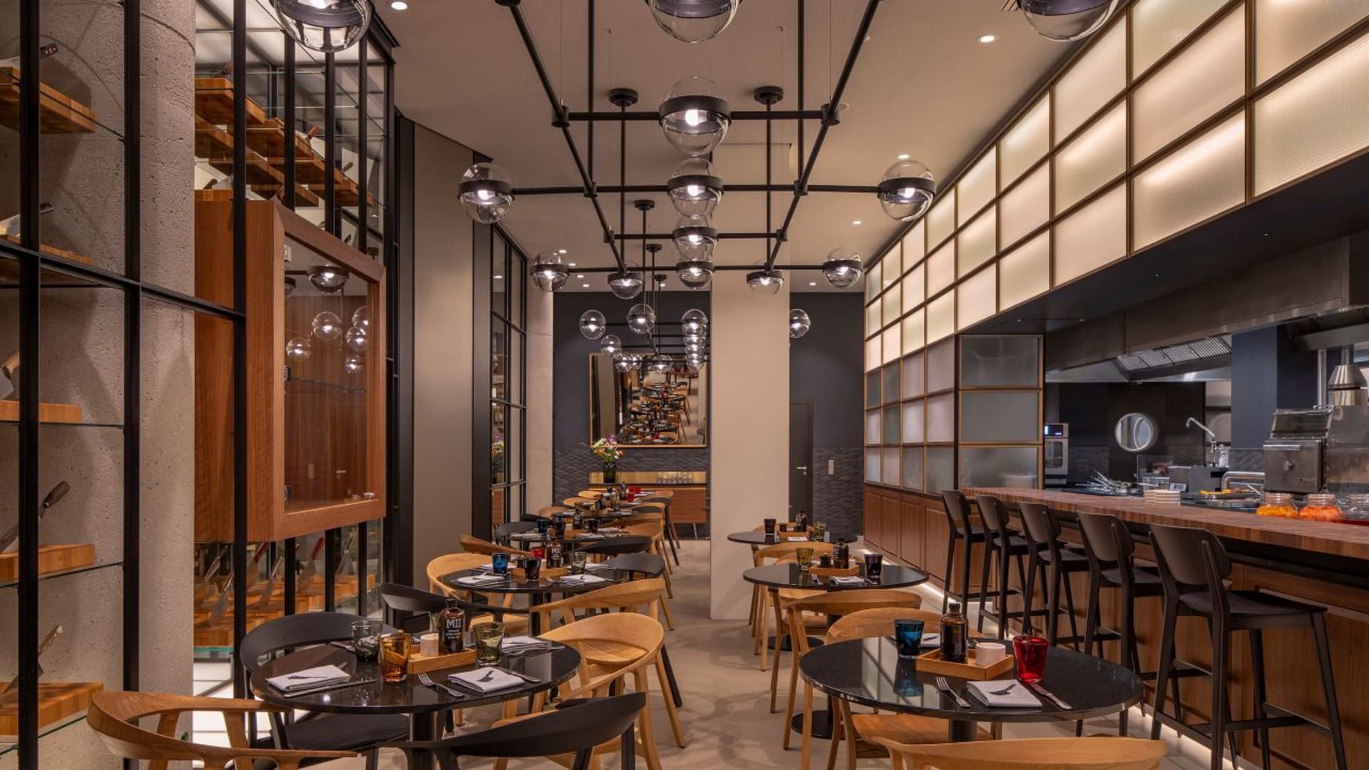 現代工業風餐廳室內,搭配俐落黑色吊燈、木質餐桌與玻璃欄杆。