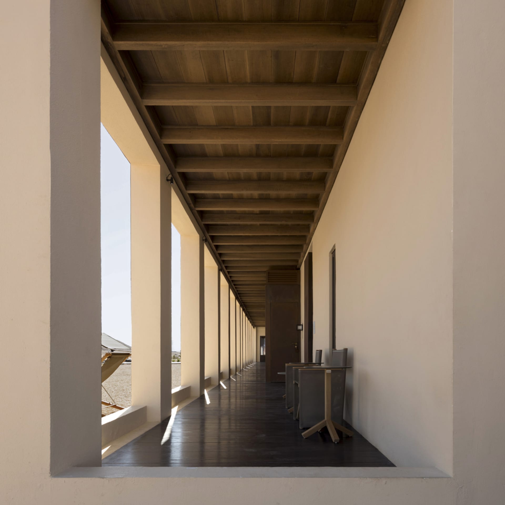 An image of a modern interior with wooden hallways and columns.