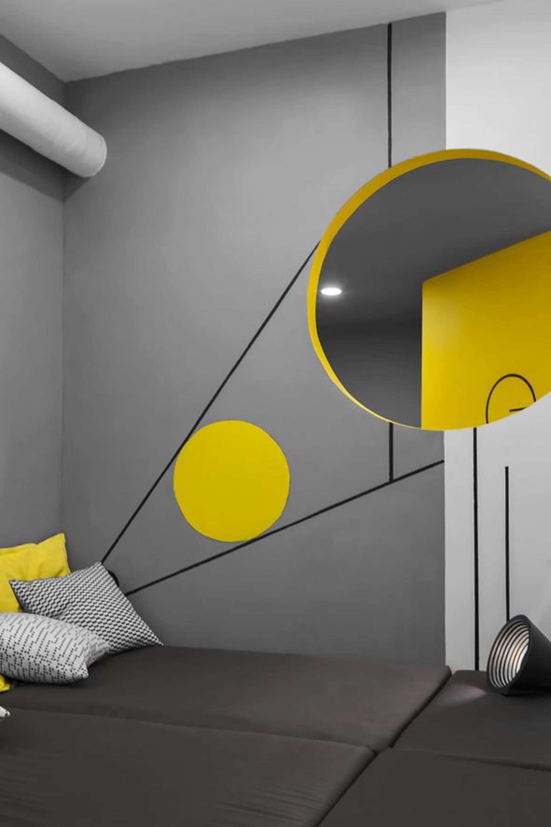 A modern living room with grey and yellow decor and a black and white striped sofa.