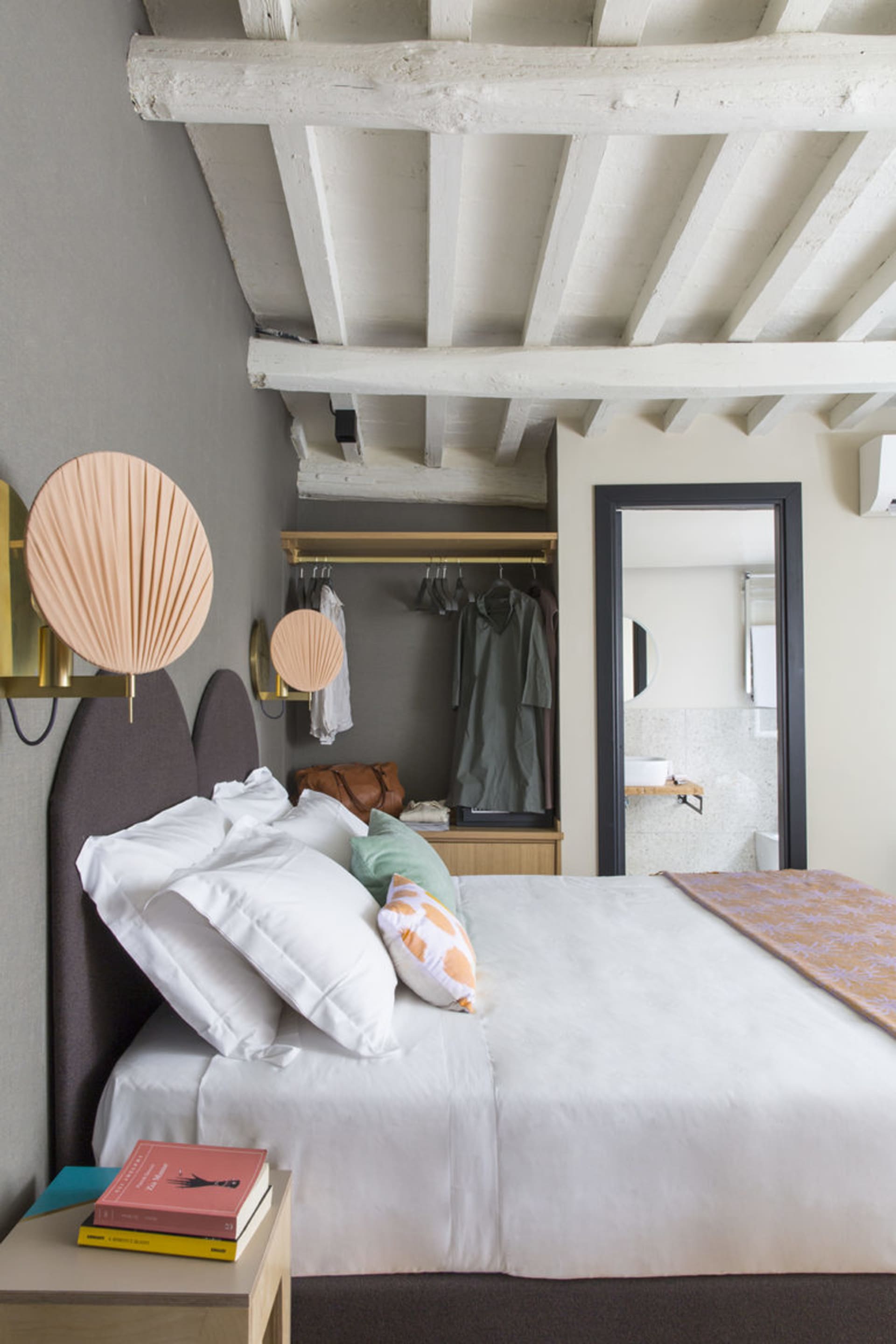 A minimalist bedroom with wood accents, white bedding, and modern decor.