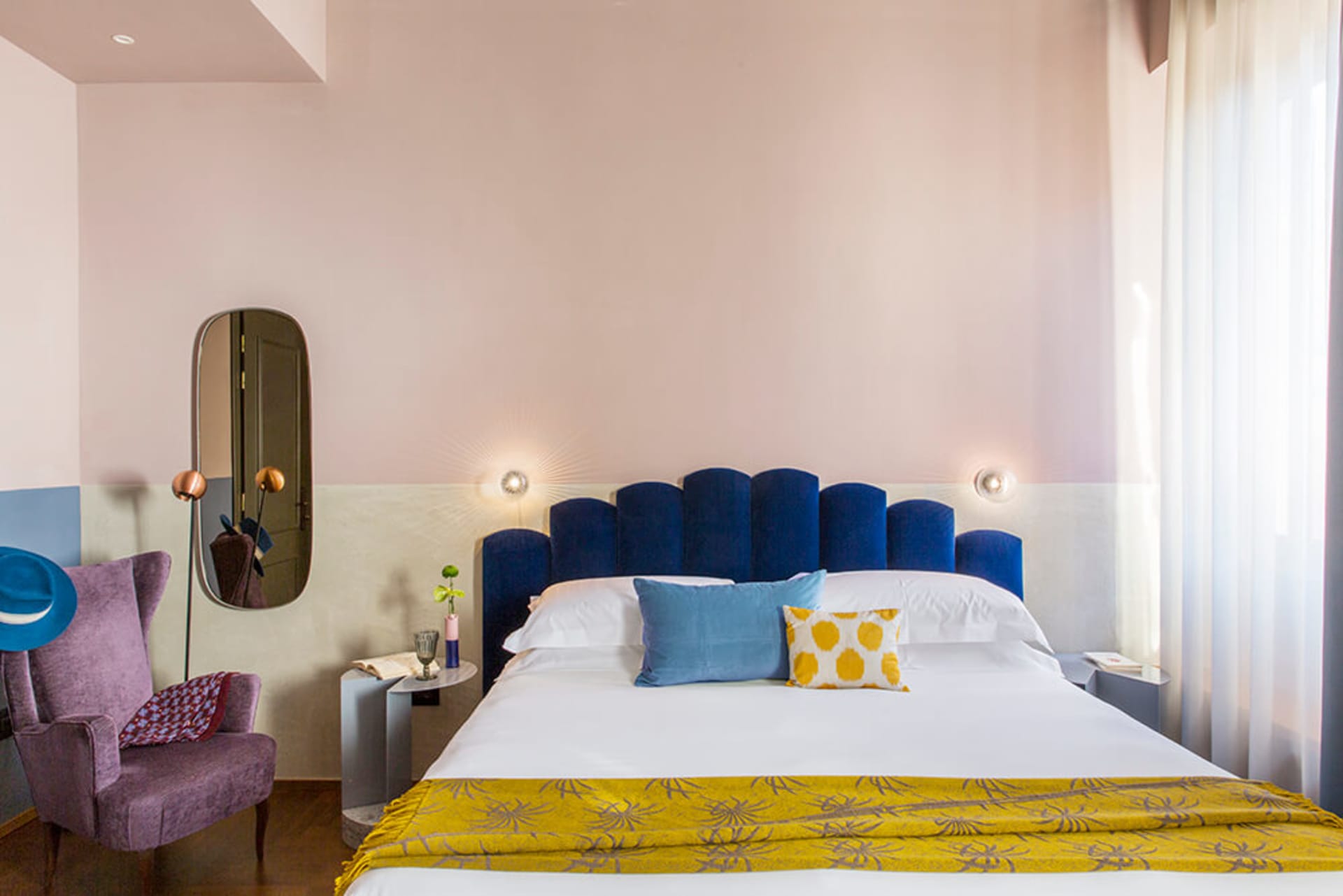 Modern bedroom featuring a navy blue upholstered headboard against a pink wall.