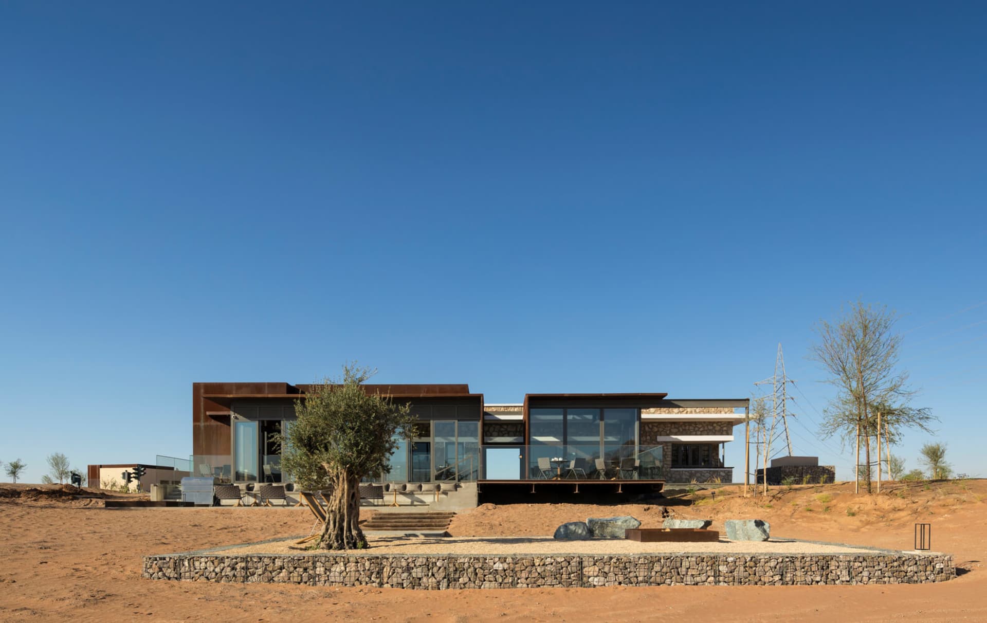 A modern residential building with large glass windows, surrounded by desert landscape.
