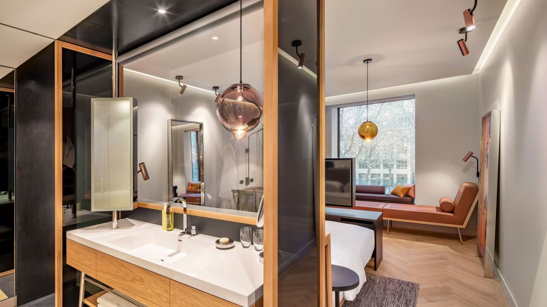 Modern residential living room with contemporary furniture, pendant lights, and a mix of materials.