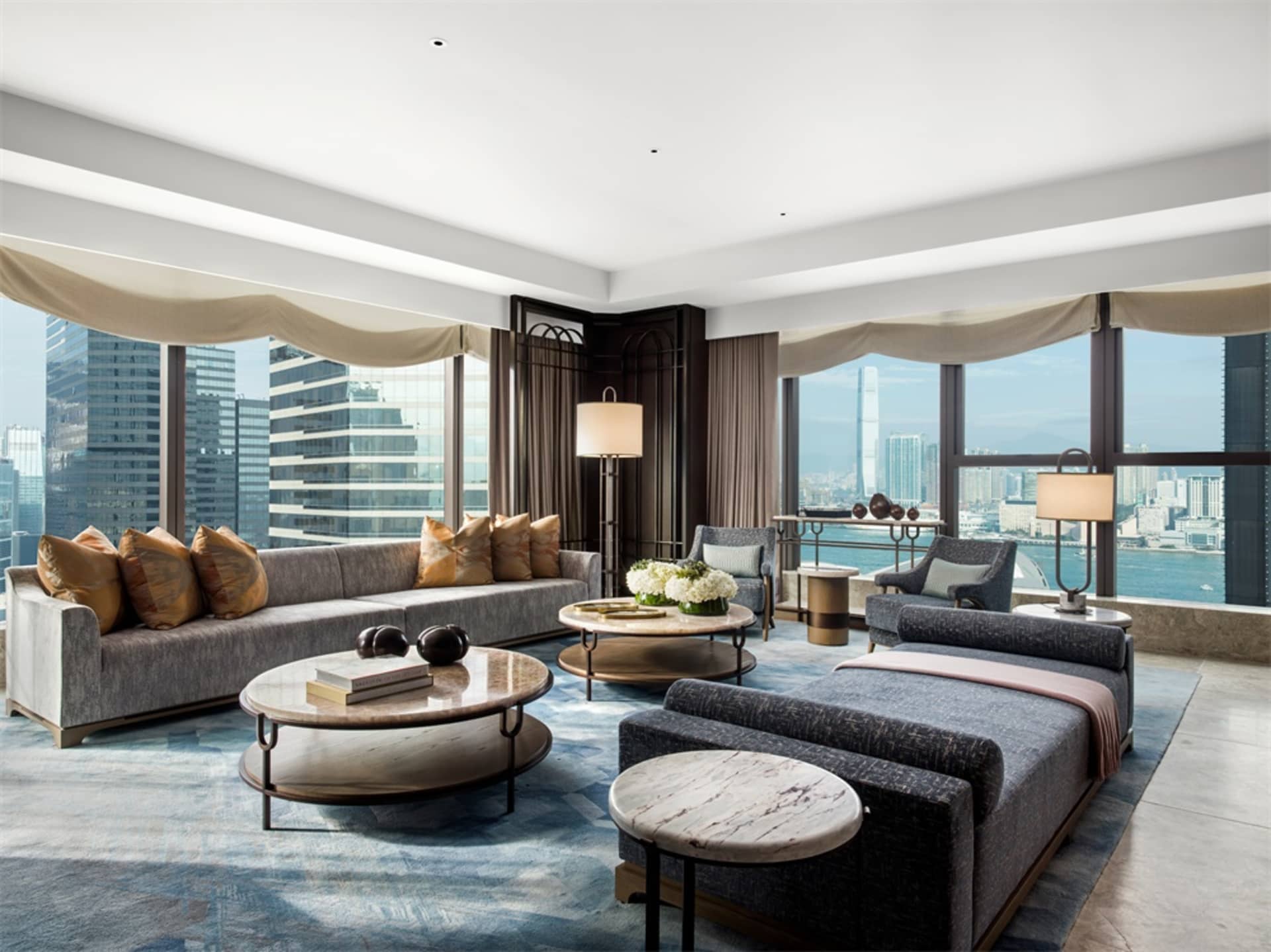 A modern living room with marble walls and flooring overlooking a cityscape.