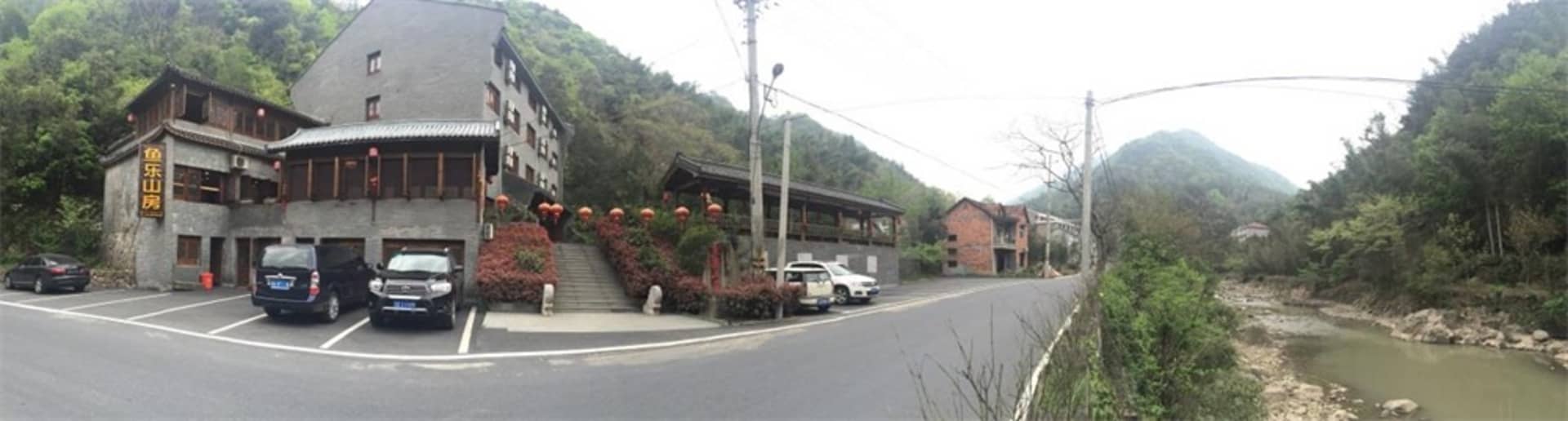 A rustic village building with a traditional architectural style and a parking area in front.