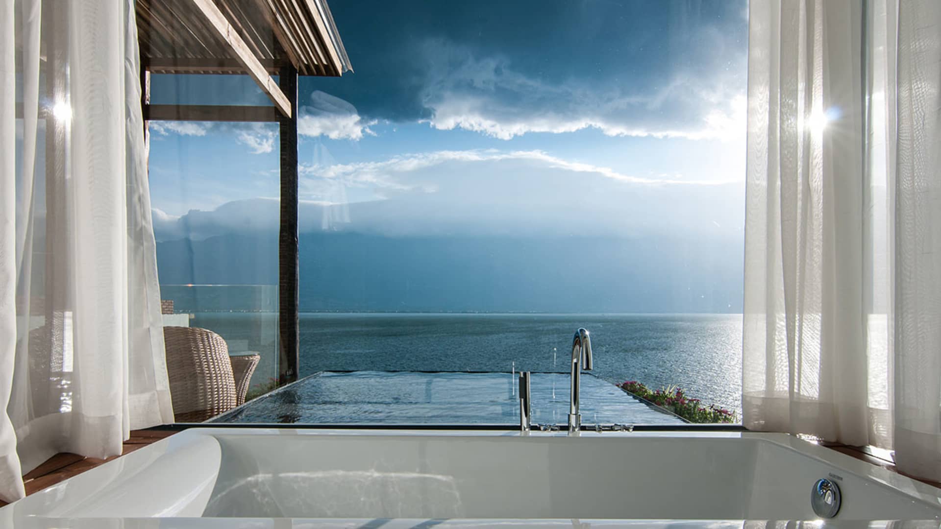 A luxurious hotel room featuring a modern bathroom with a white bathtub overlooking the ocean.