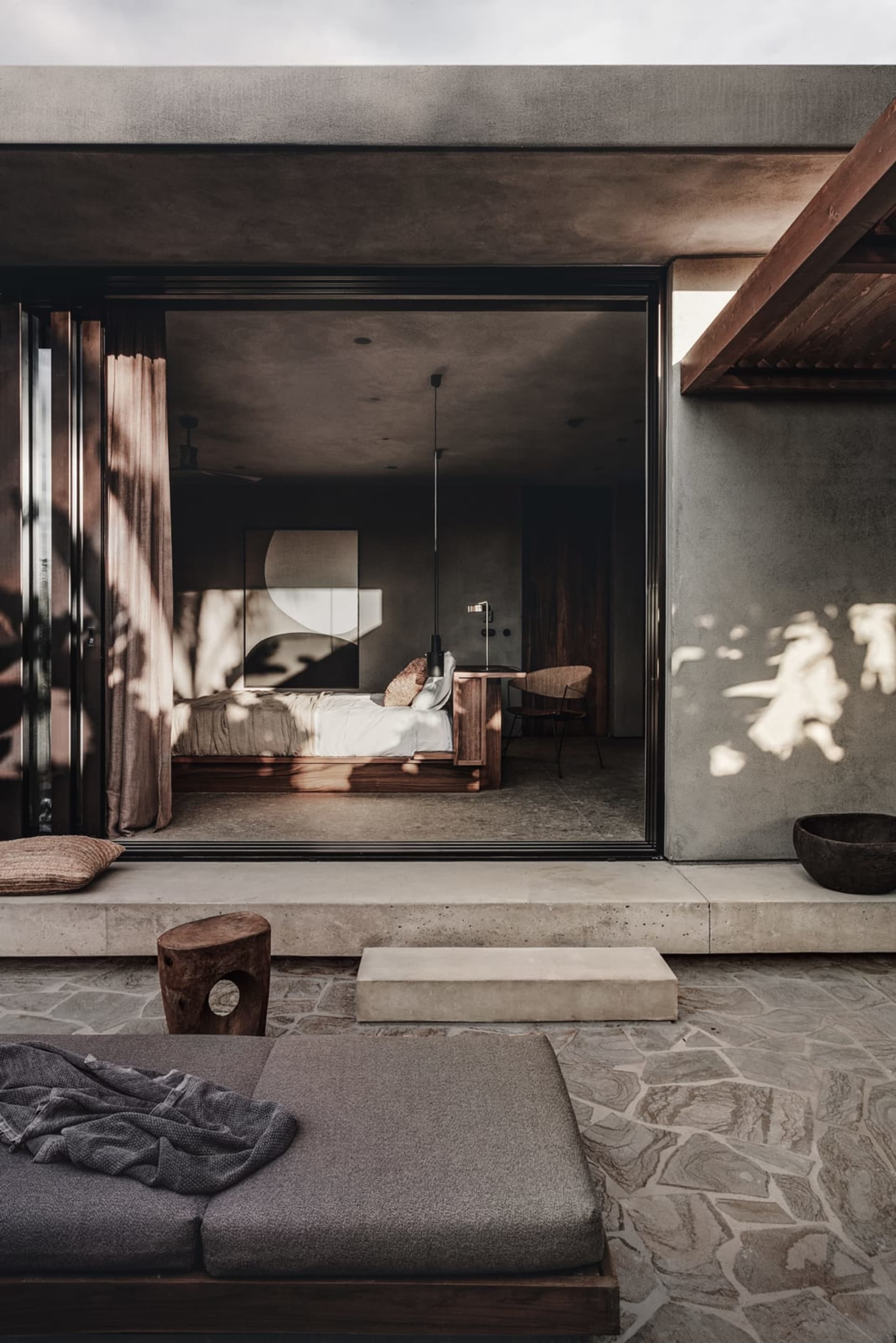 Minimalist bedroom with concrete walls and a bed.