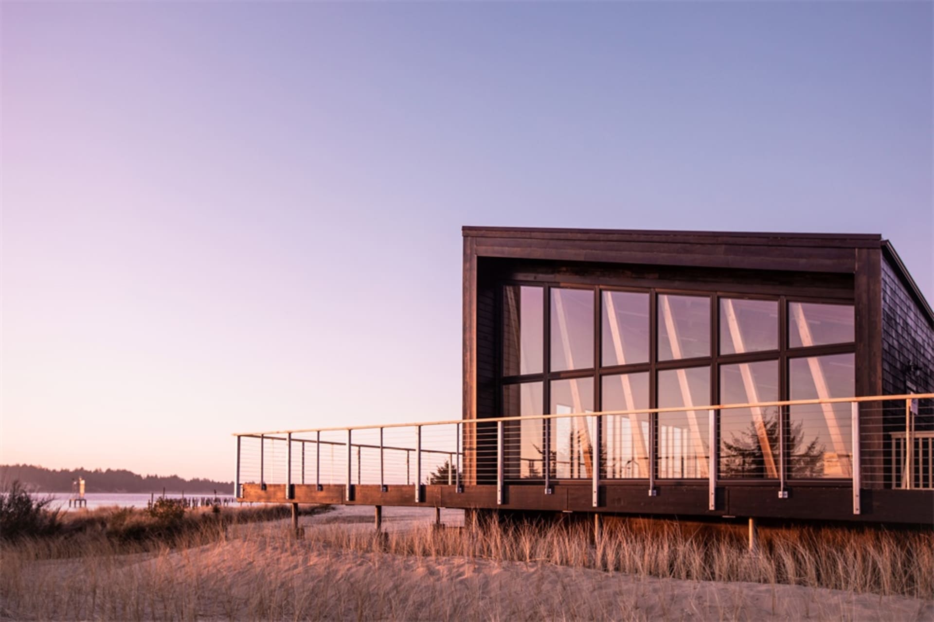 A modern, minimalist residential building with large glass windows and wooden exterior.