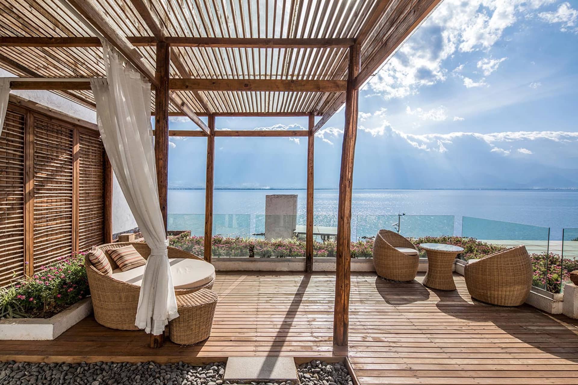 A minimalist residential patio with a wood roof overlooking the ocean.