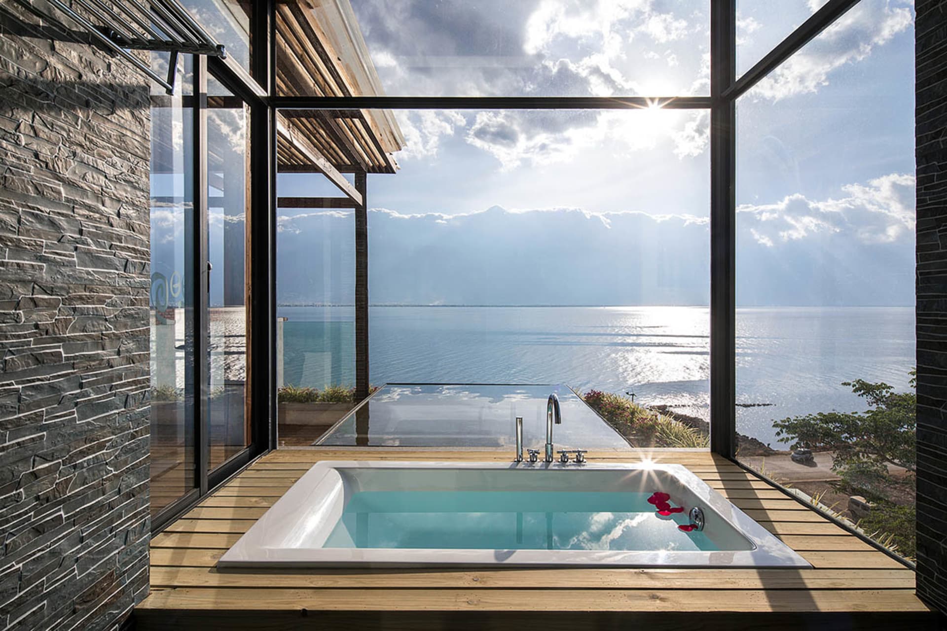 Modern bathroom overlooking the sea with a glass wall.
