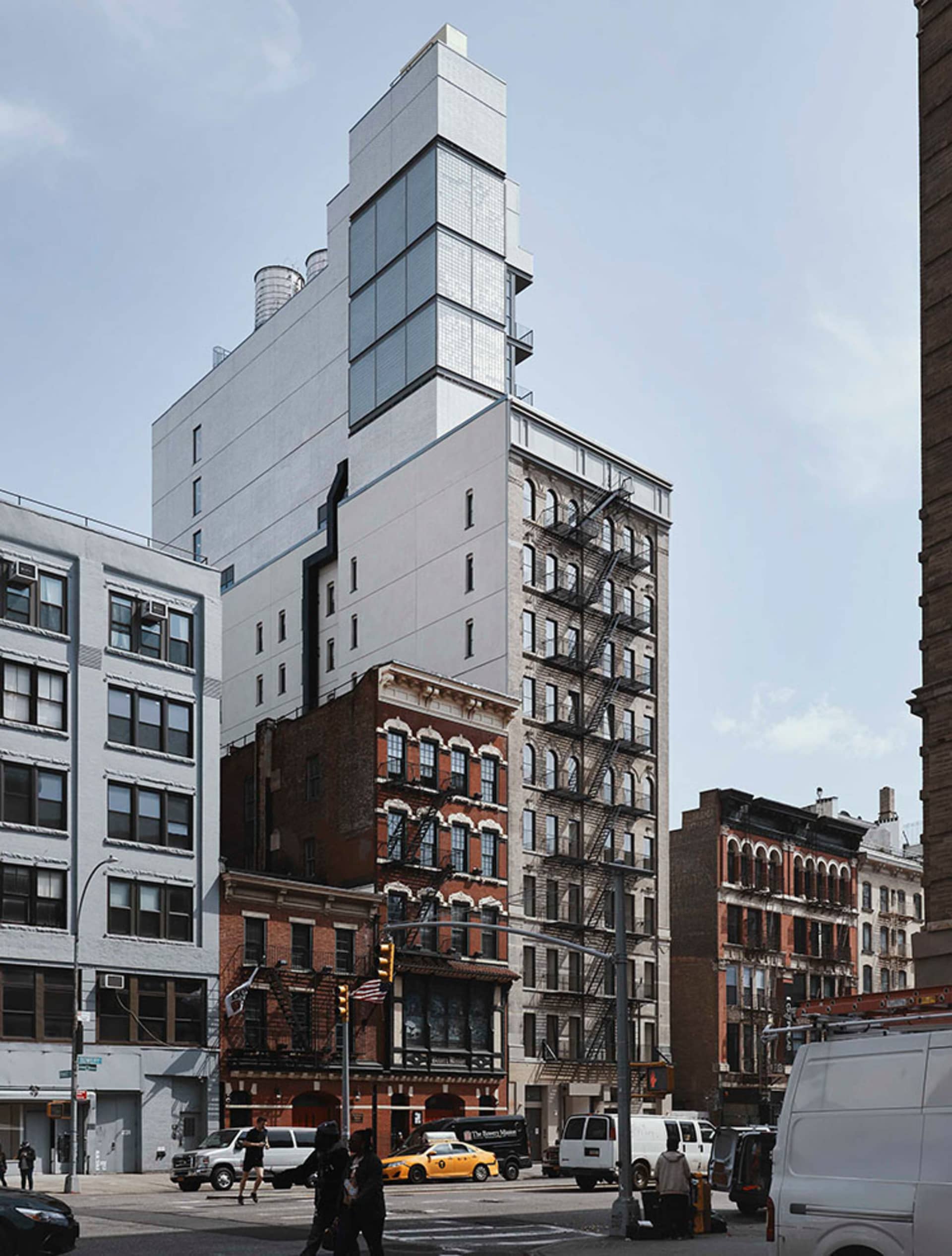 A modern glass building with a unique geometric design and industrial elements in the surrounding area.