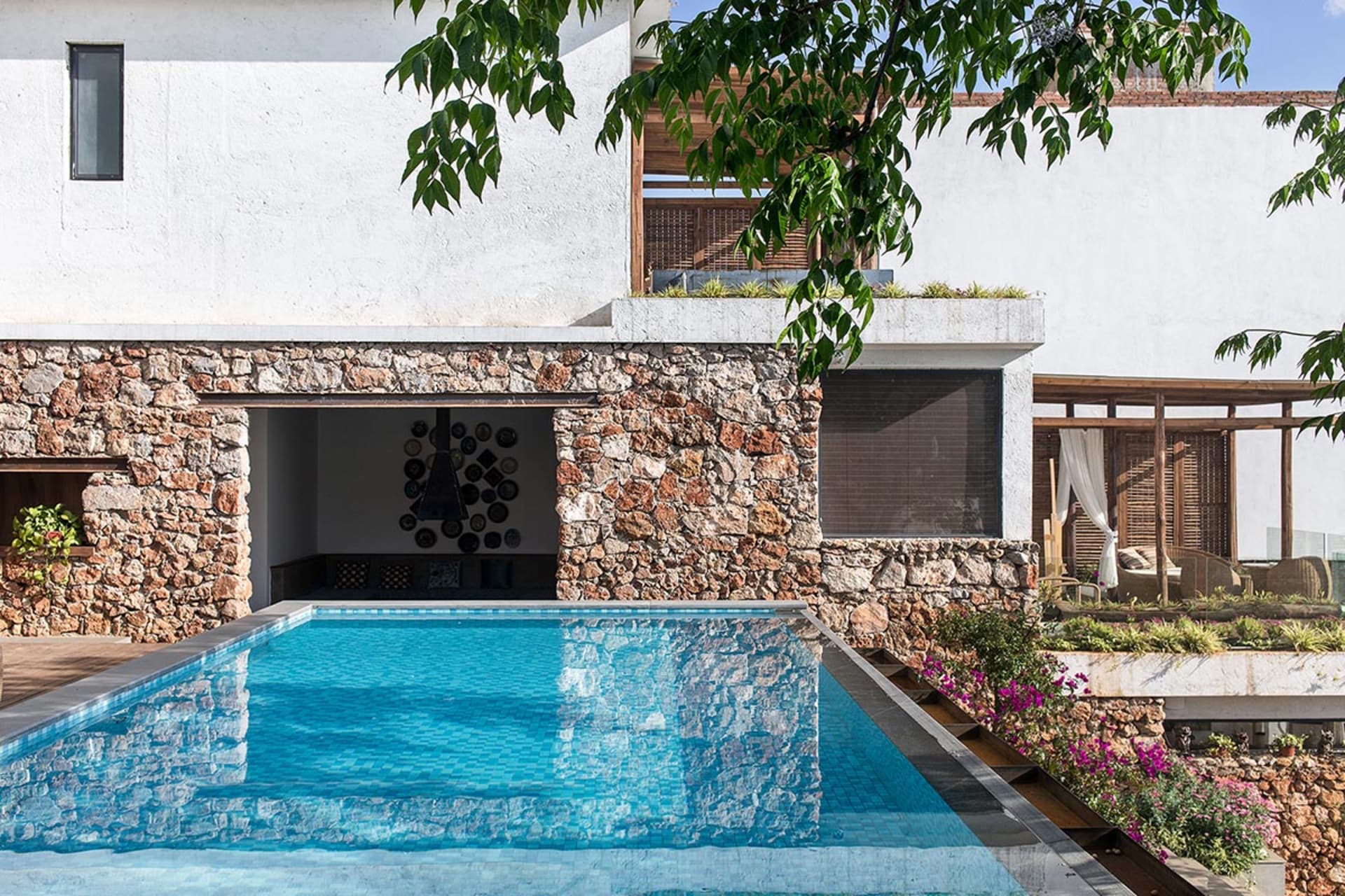Modern house exterior featuring a pool with concrete walls and a green tree nearby.
