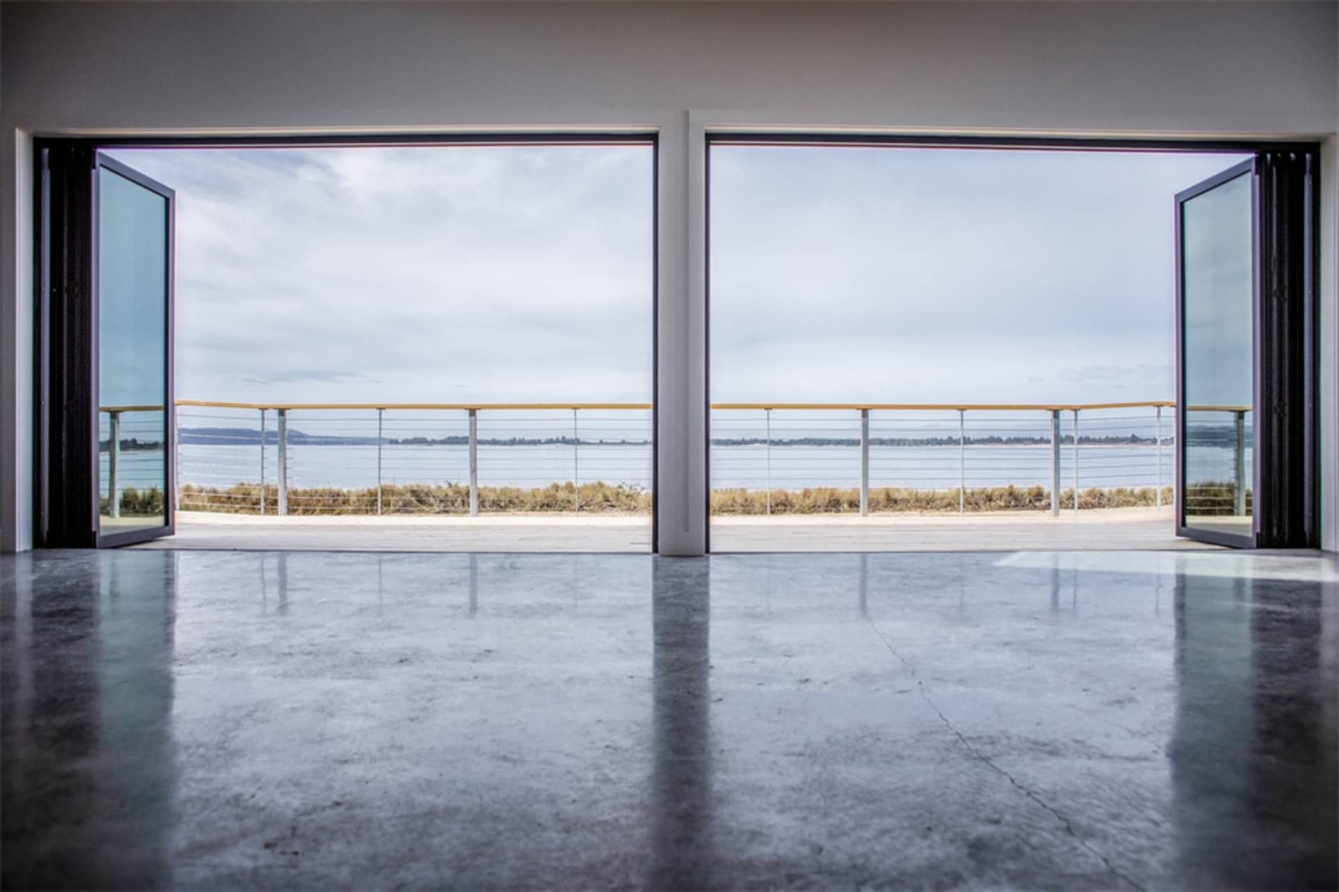 Modern interior space with concrete flooring and large windows overlooking a lake.