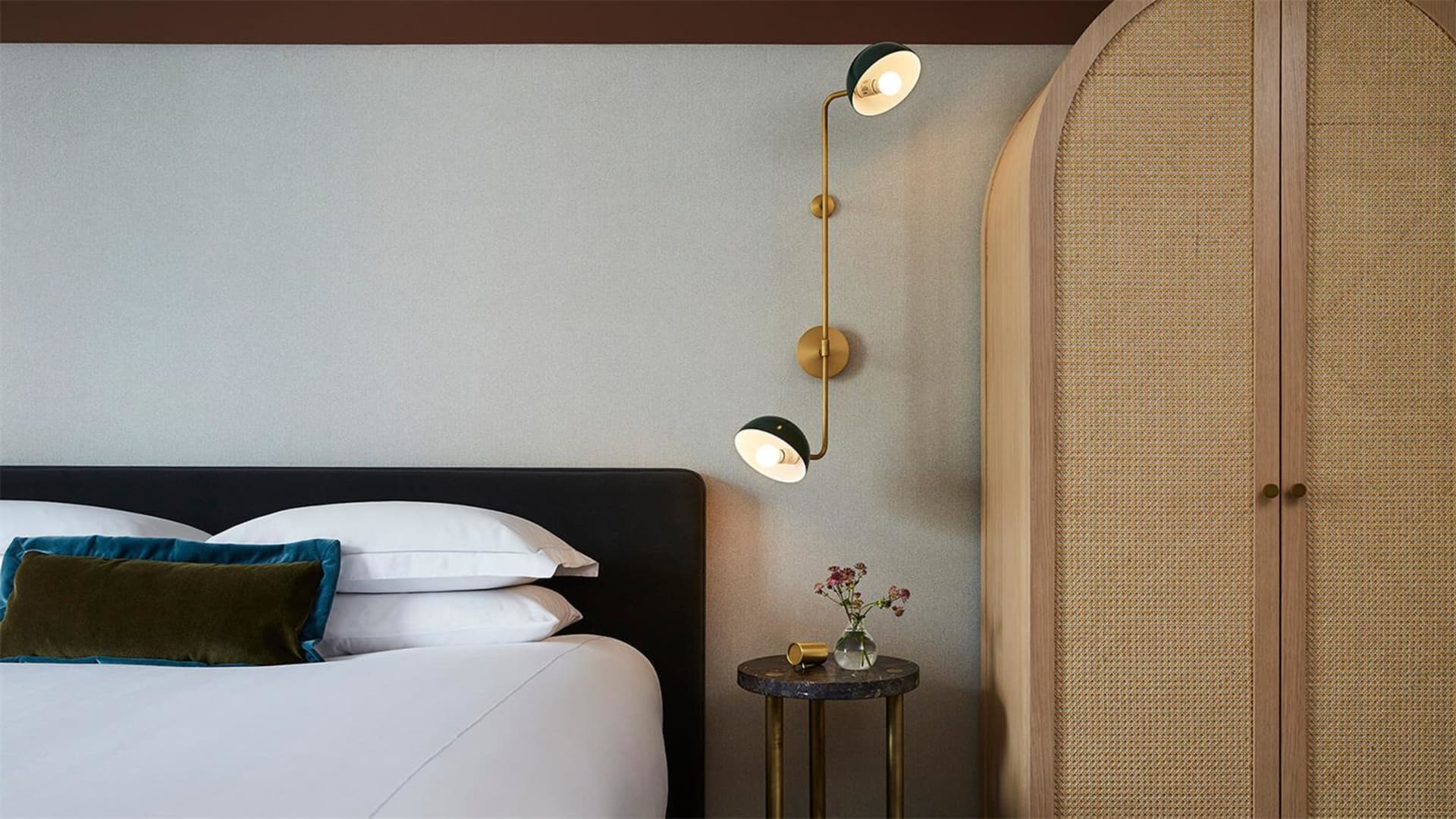 A modern minimalist bedroom with a white bed and teal accents.