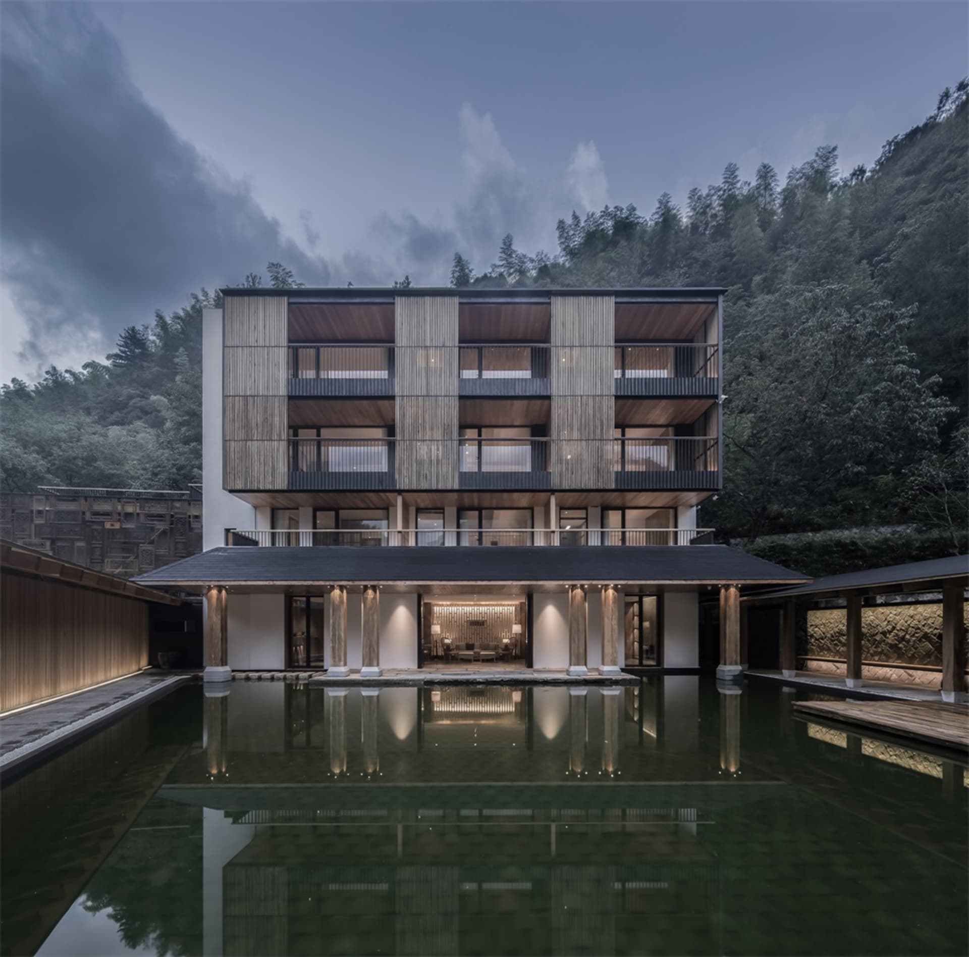 Modern residential building with wooden facade and reflection in water body.