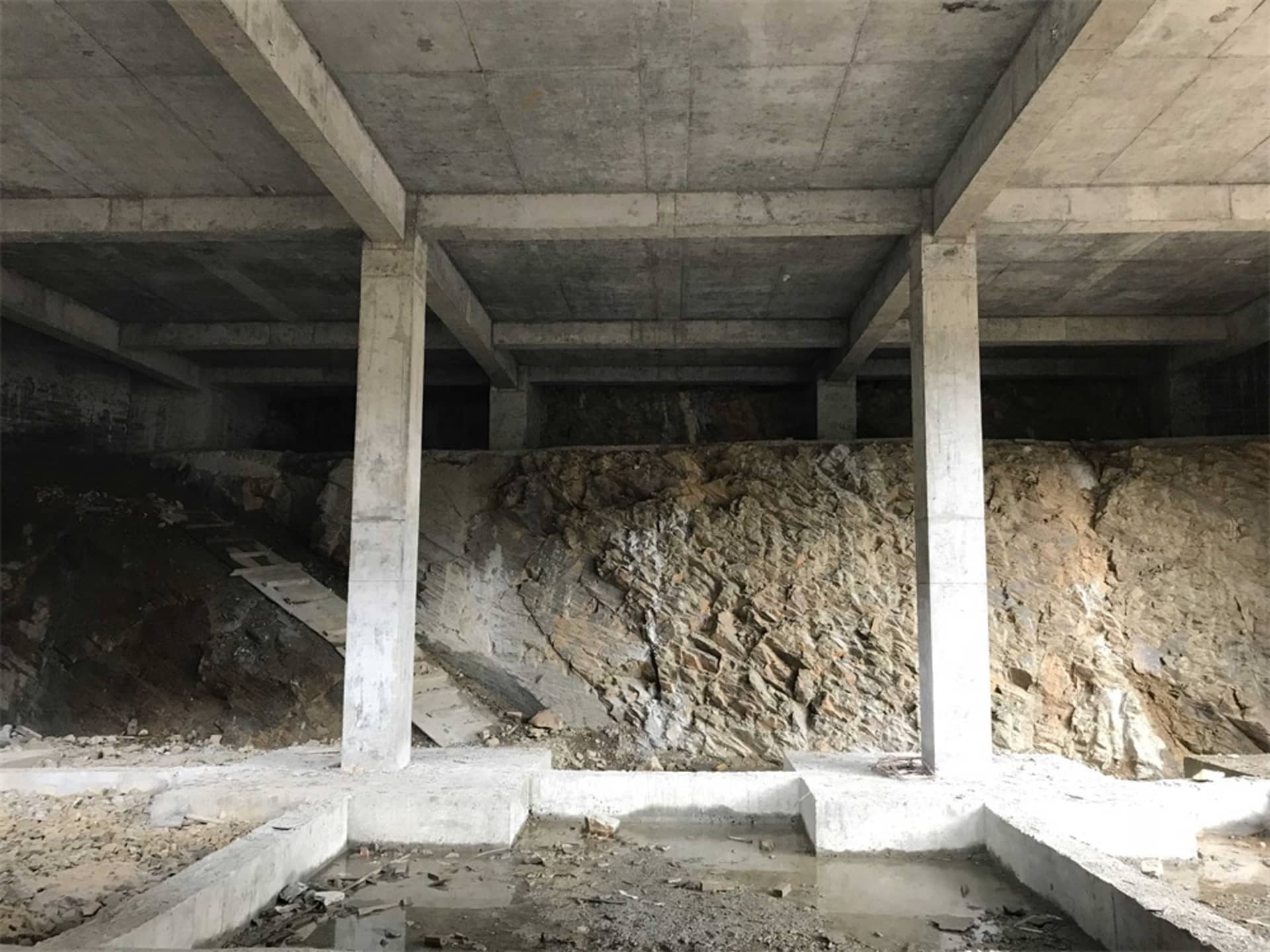 建築物下的混凝土基礎,露出岩層與施工碎屑。