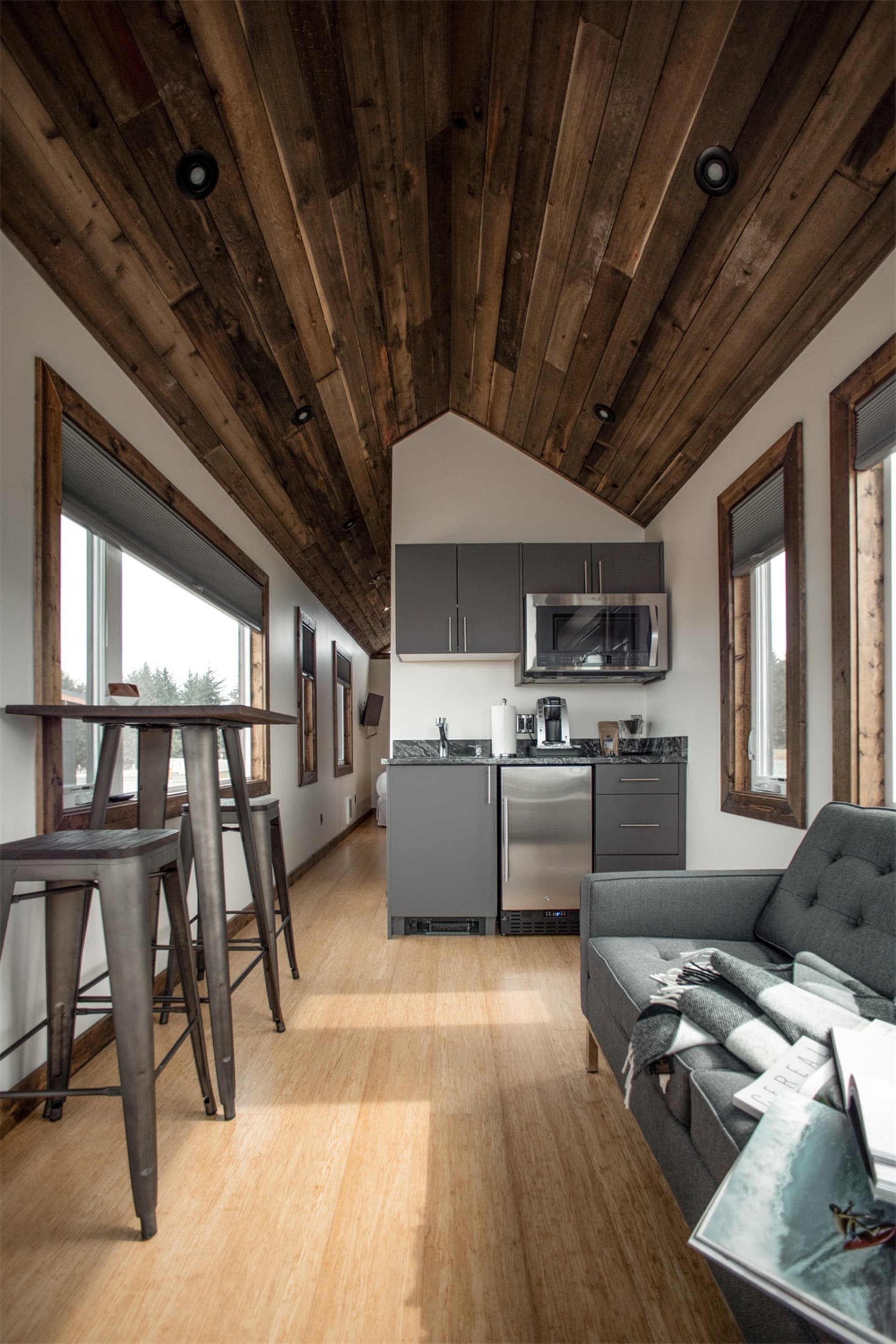 A minimalist kitchen with wooden ceiling, stainless steel appliances, and modern furniture.