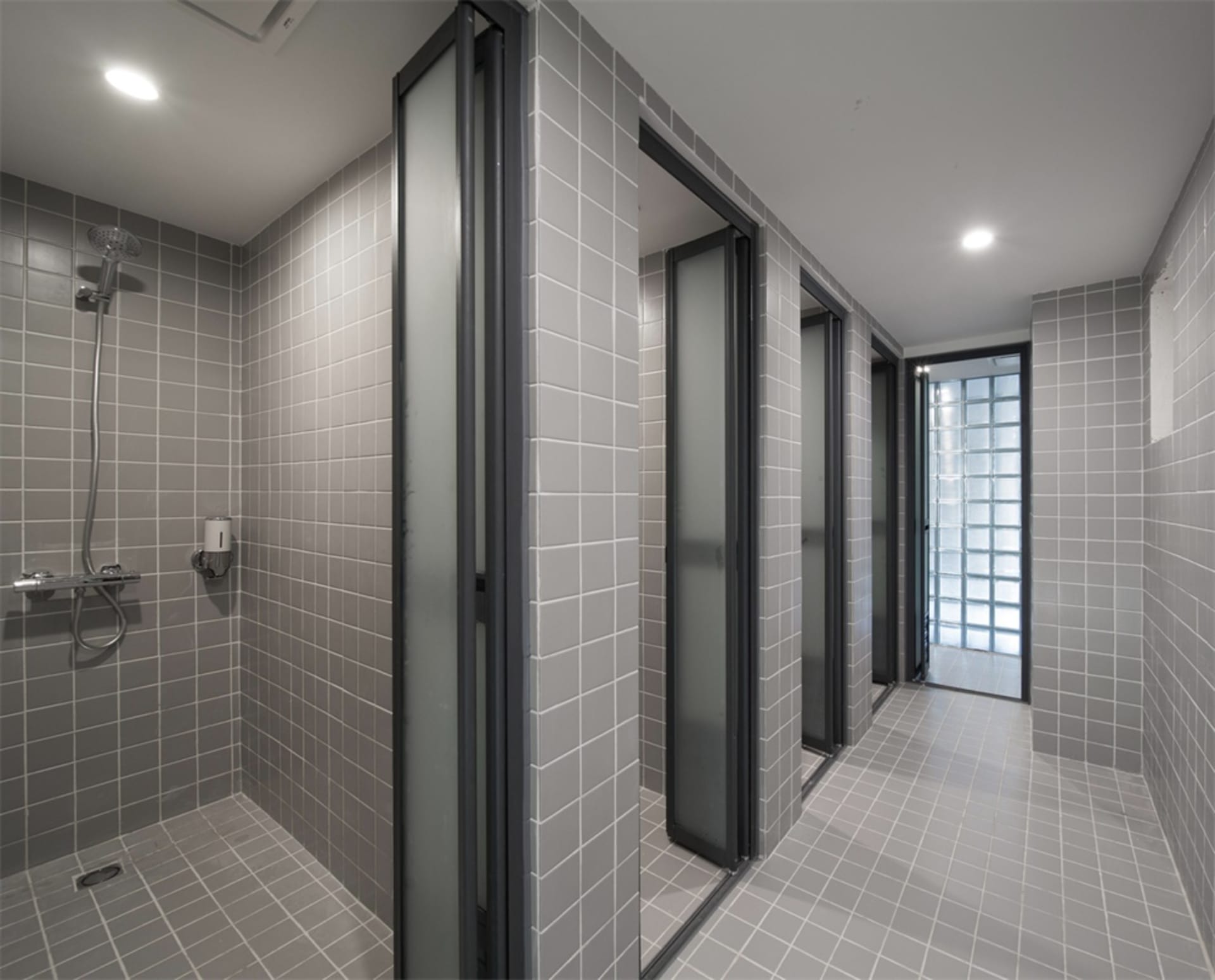 Modern bathroom with gray tiles and frosted glass doors.