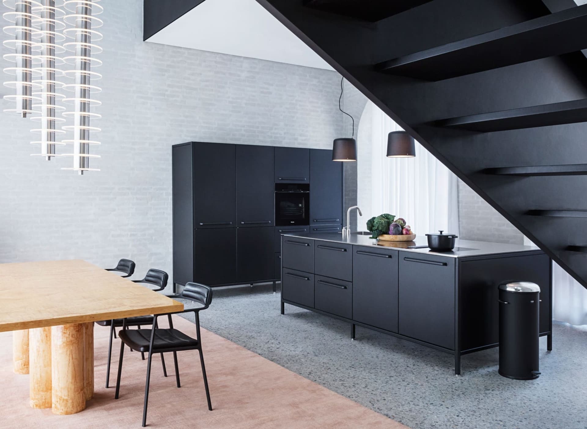 Modern, minimalist kitchen with black cabinets, stainless steel appliances, and natural light.