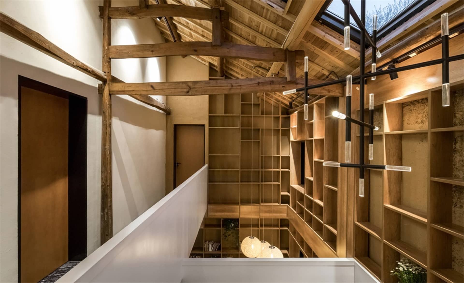 A modern bookshelf library with wooden shelves and exposed wooden beams on the ceiling.