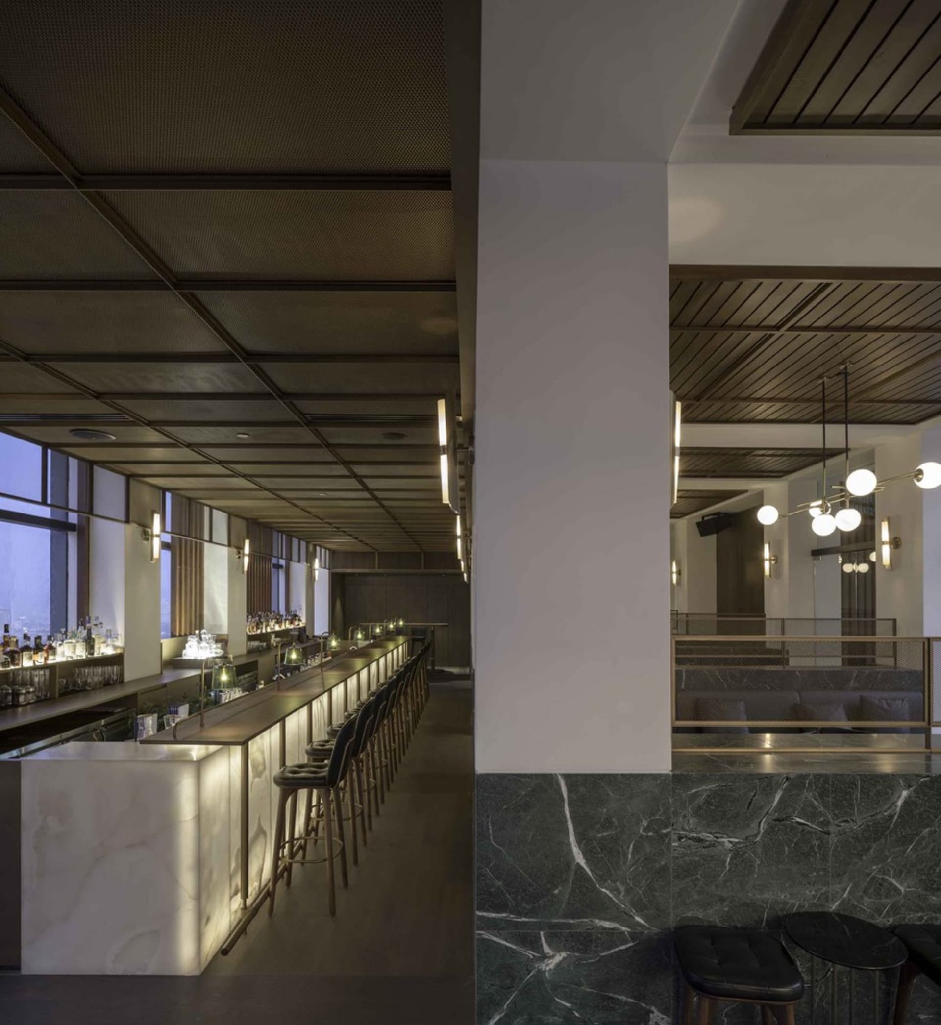 Interior view of a modern industrial restaurant bar featuring marble and concrete materials