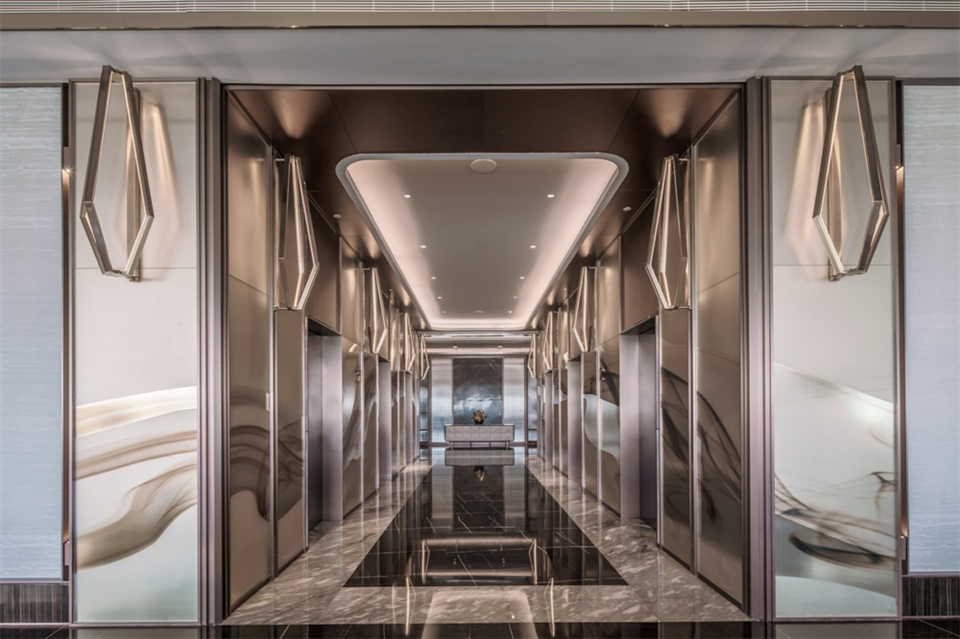 An elegant modern lobby featuring sleek, mirror-polished metal walls and a reflective floor.