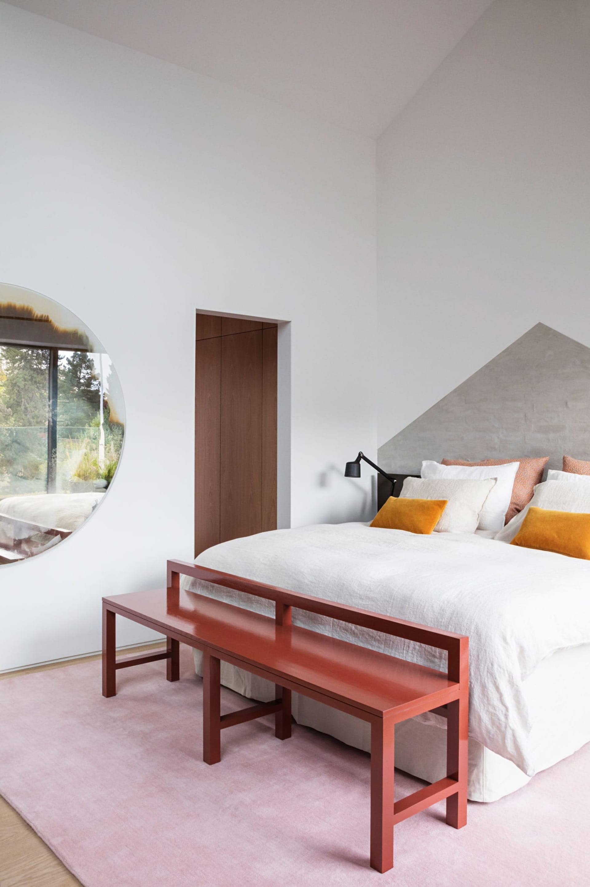 A modern minimalist bedroom featuring a concrete bench and a bed with yellow accent pillows.