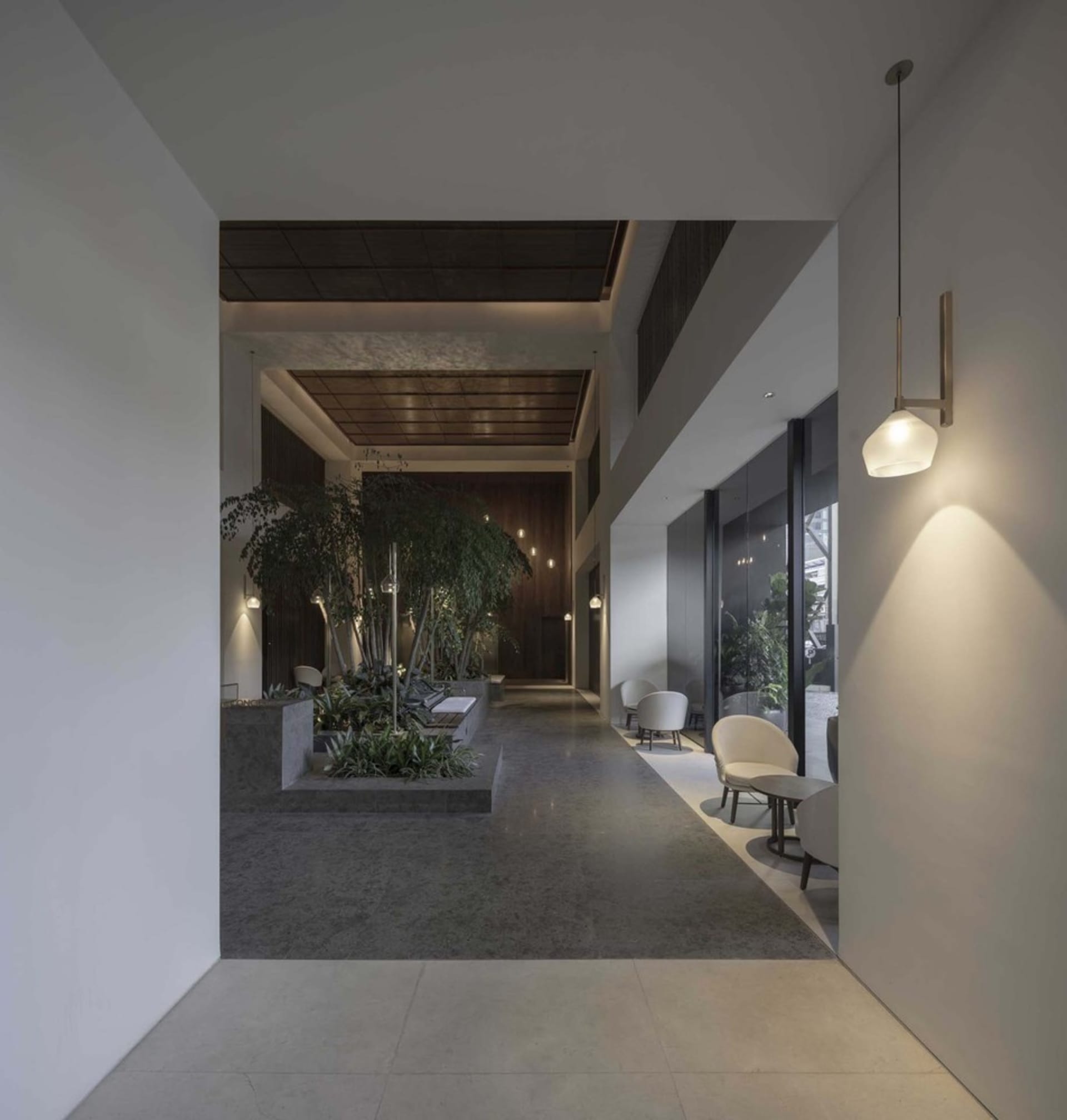 A modern office lobby featuring concrete, glass, and wooden materials.