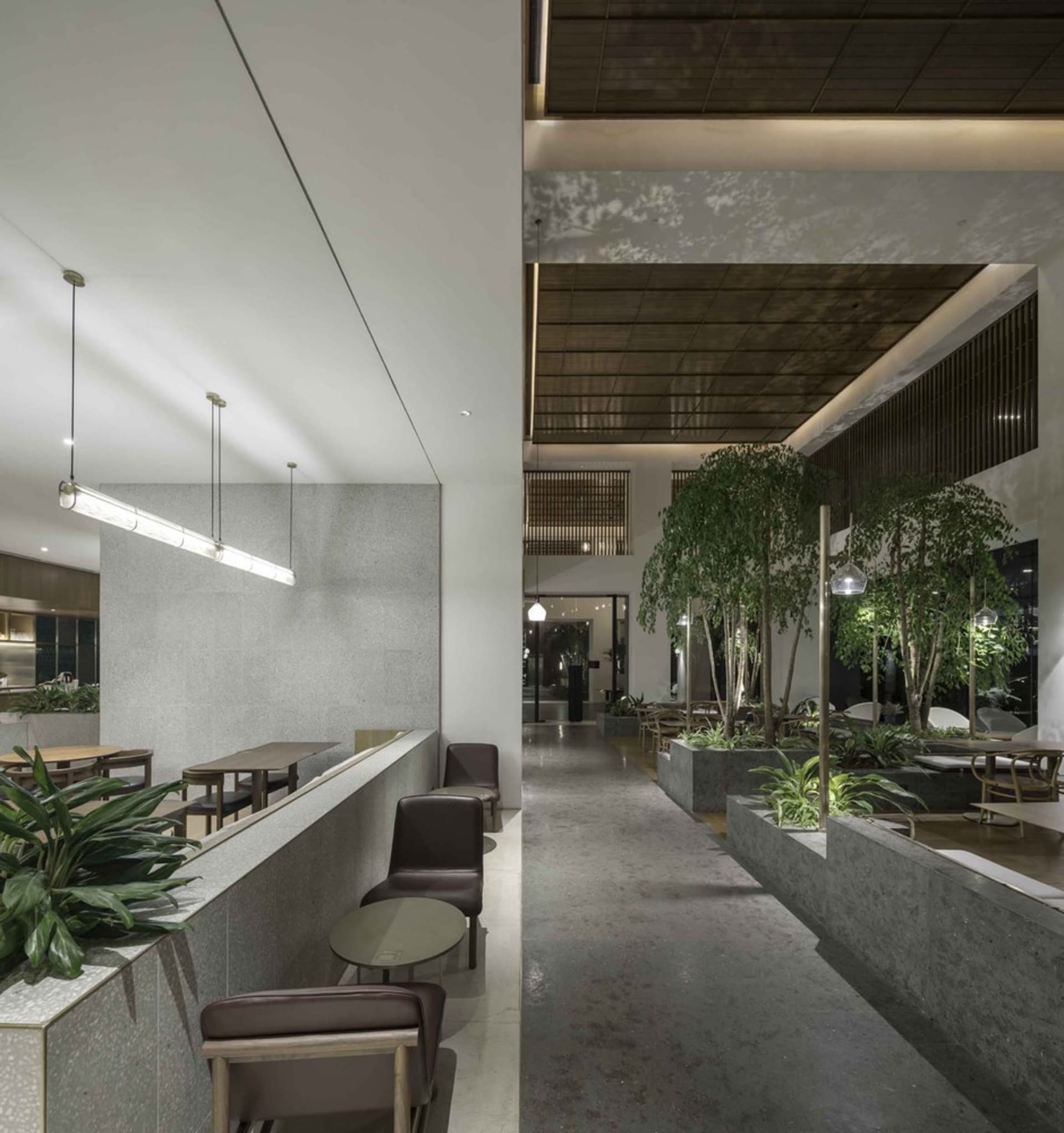 Industrial-style restaurant interior with concrete walls, metal railings, and green plants.