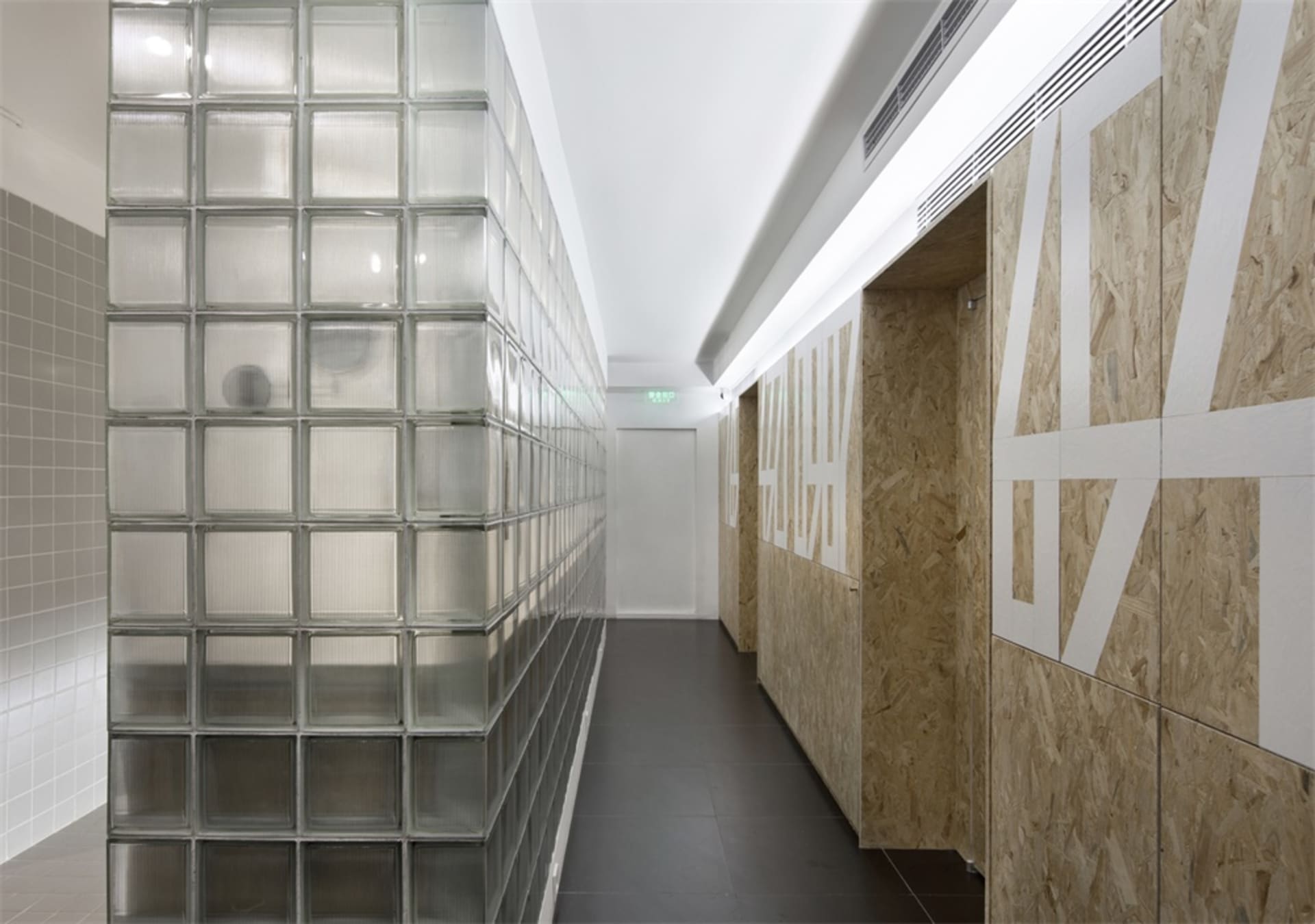 Modern office corridor featuring glass block walls and wooden OSB partitions.