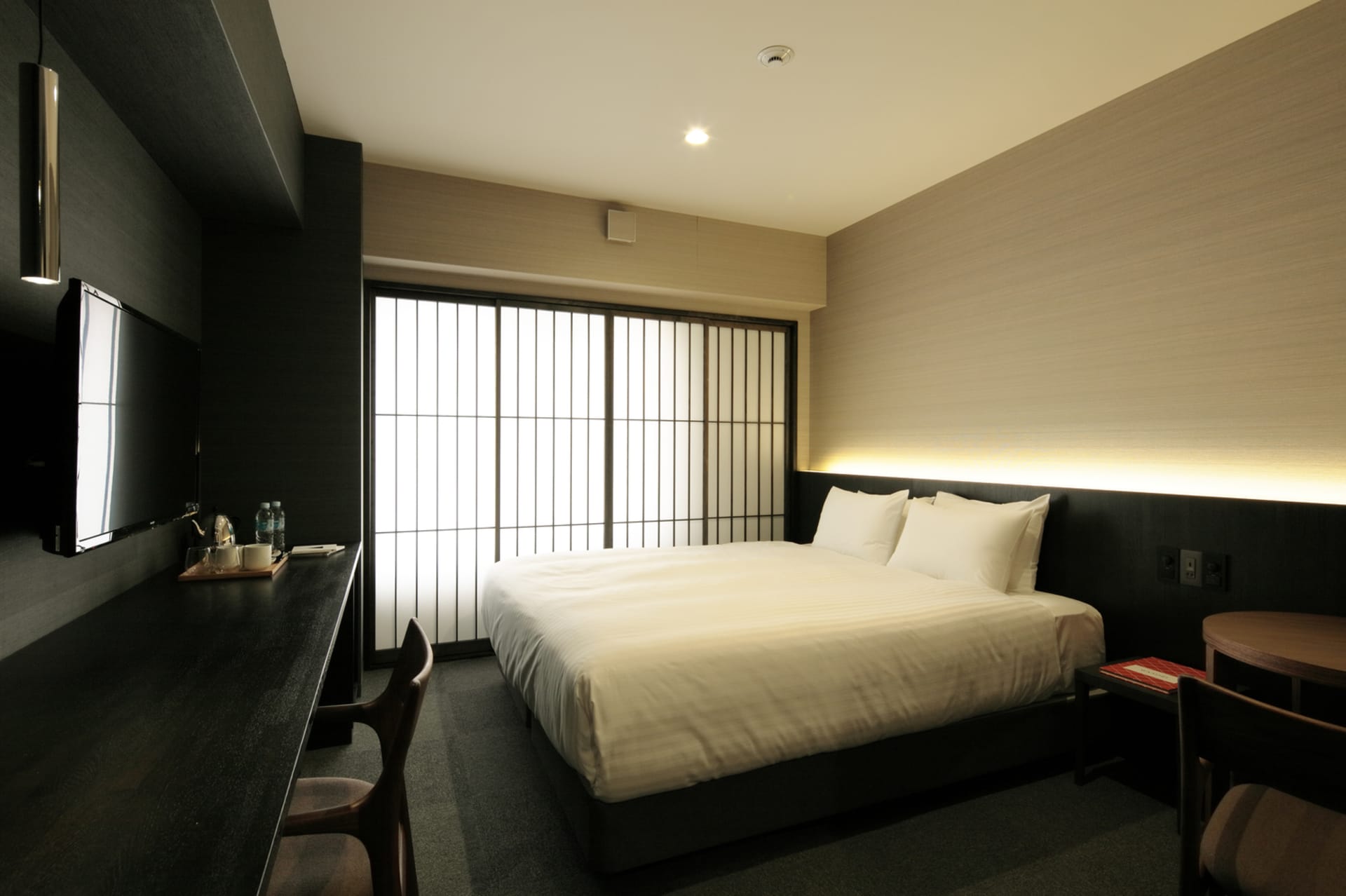 Modern minimalist bedroom featuring a large bed with white linens, surrounded by sleek black walls and a sliding door with tr