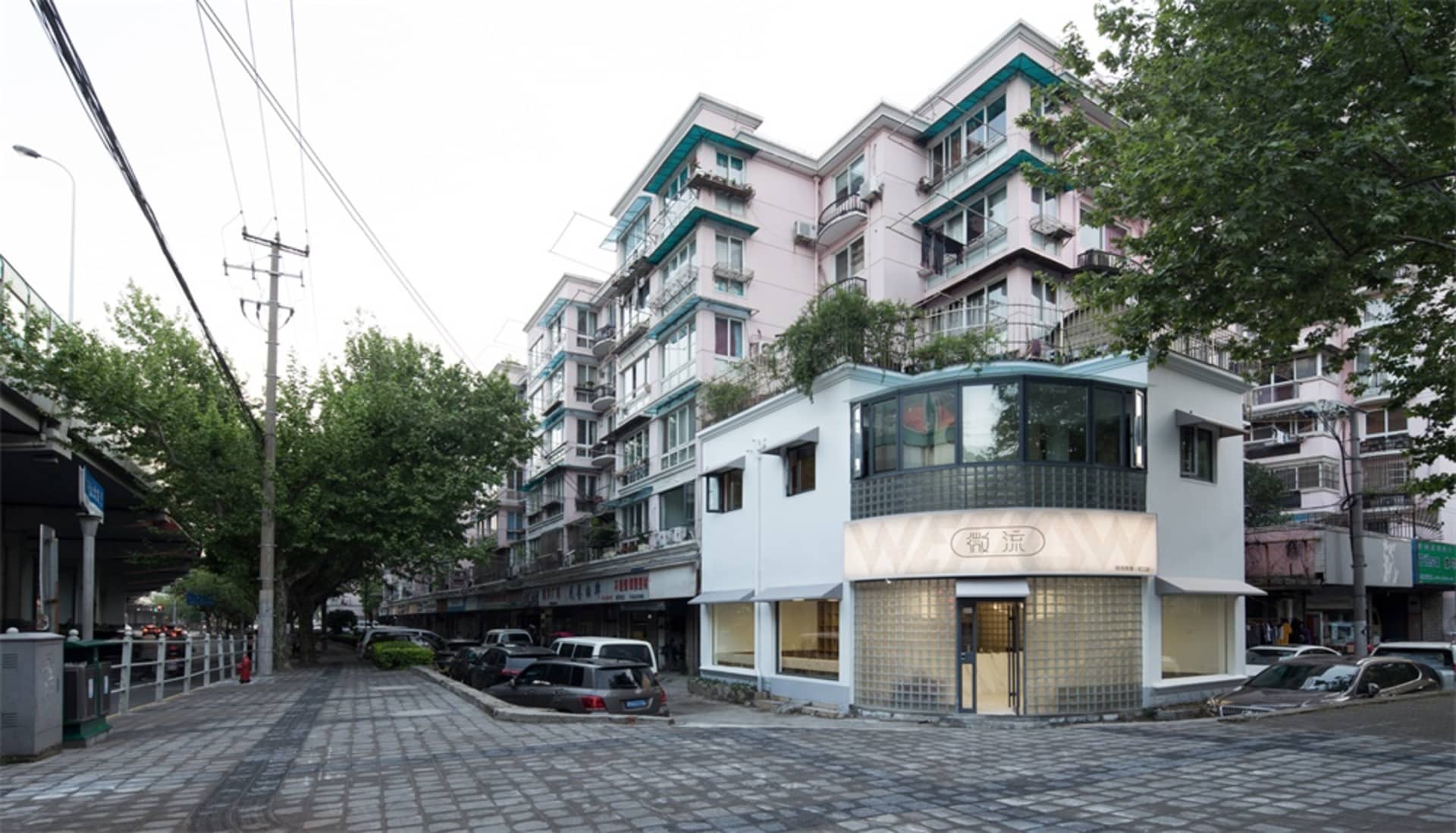 A street view of urban architecture featuring windows, plant balconies, and various building materials.