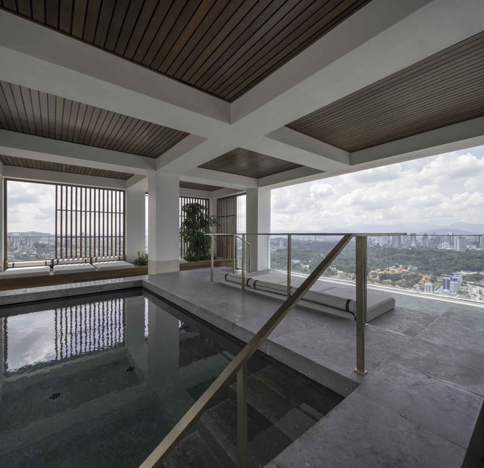 現代室內泳池平台採用混凝土地板與玻璃欄杆,眺望城市景觀。
