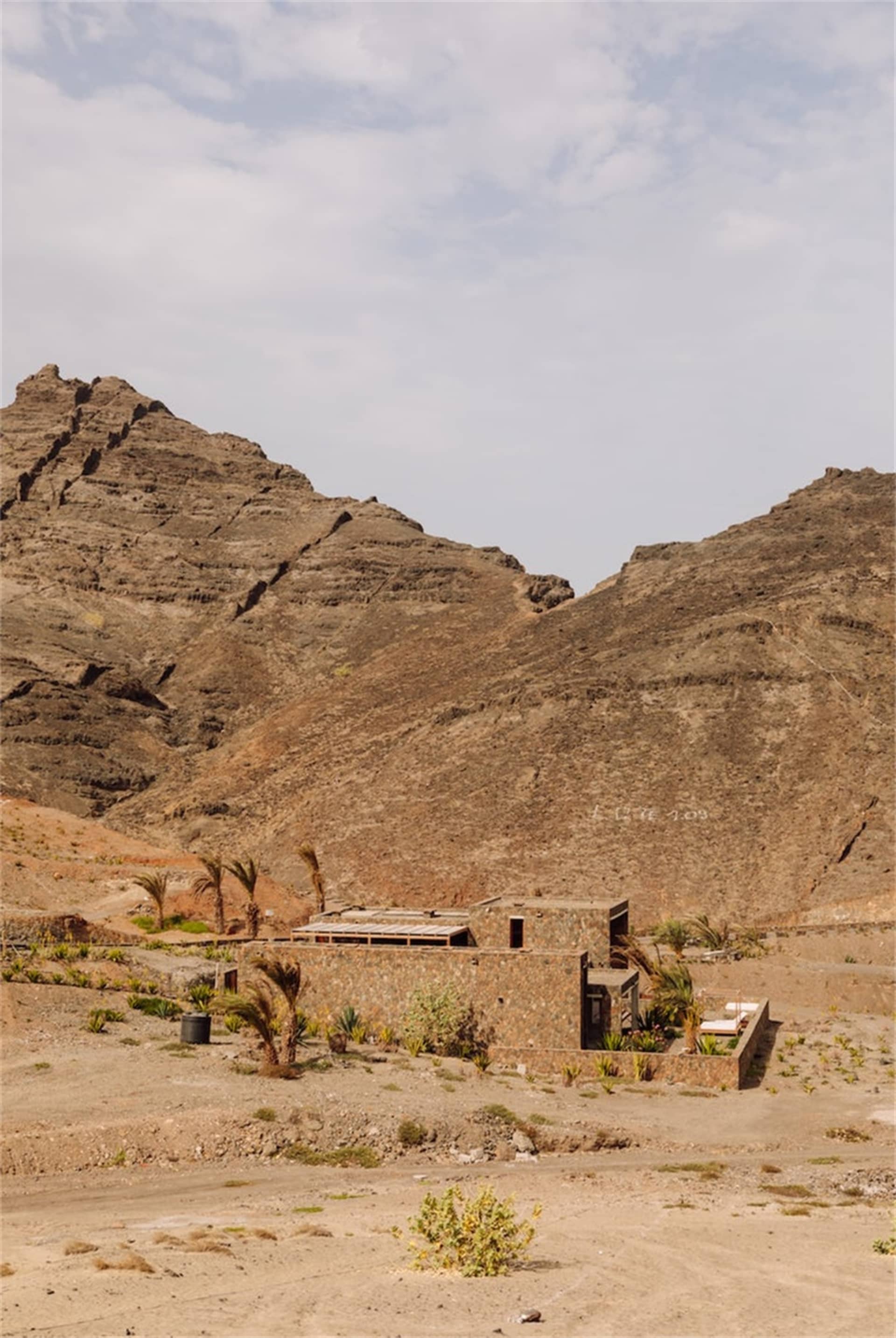 A minimalist house with stone walls in a desert landscape.