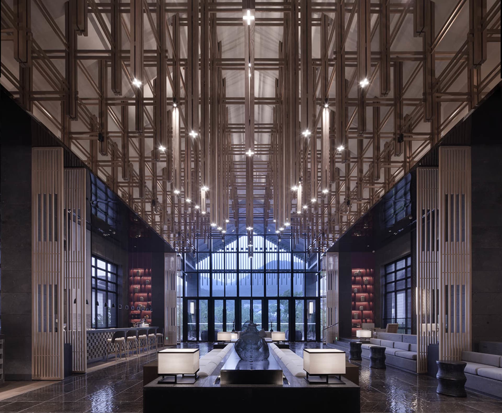 Modern hotel lobby featuring concrete and wood materials with high ceilings and large windows.