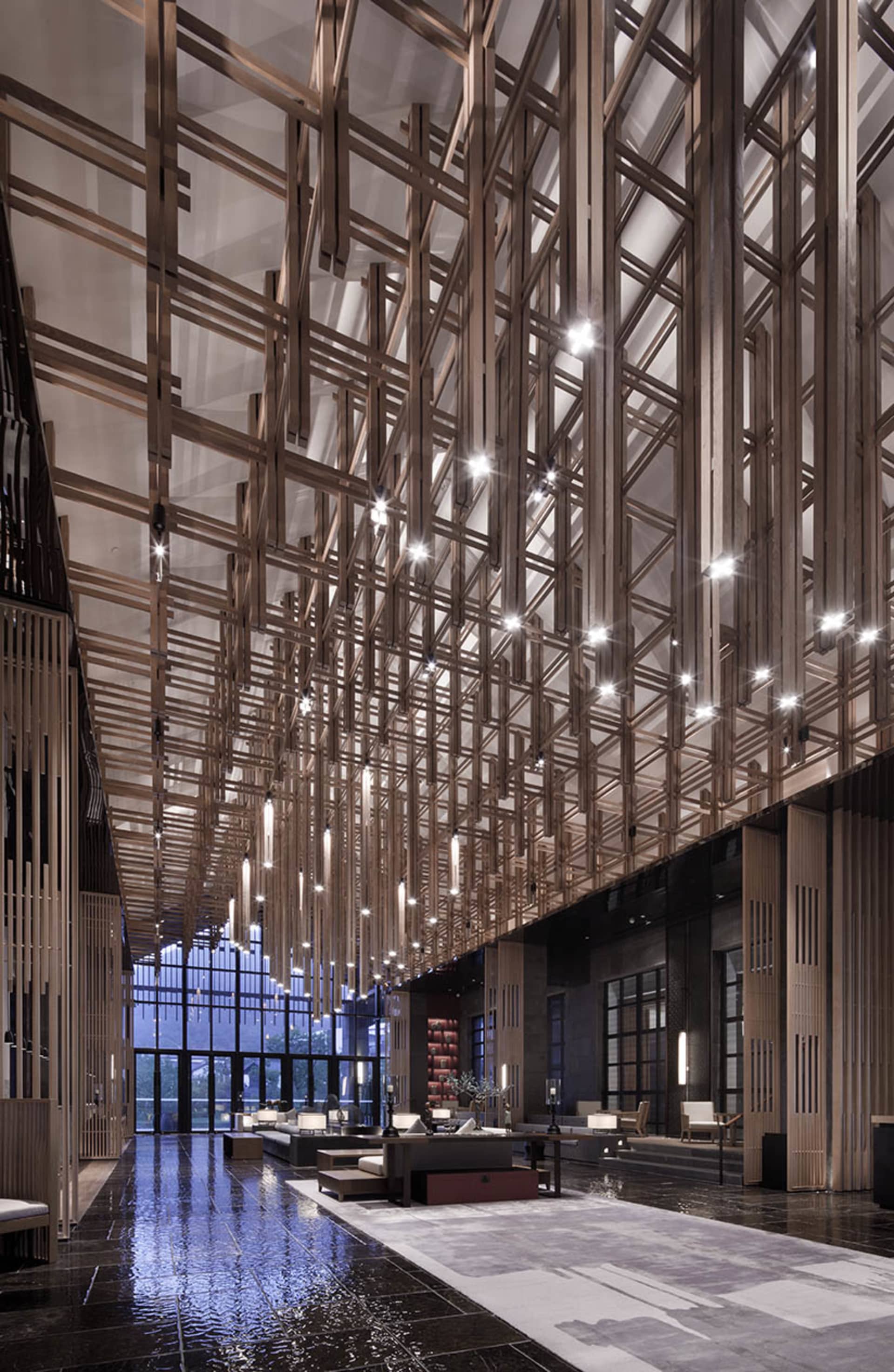 A modern lobby with glass walls, high ceiling, and wooden interior decor.