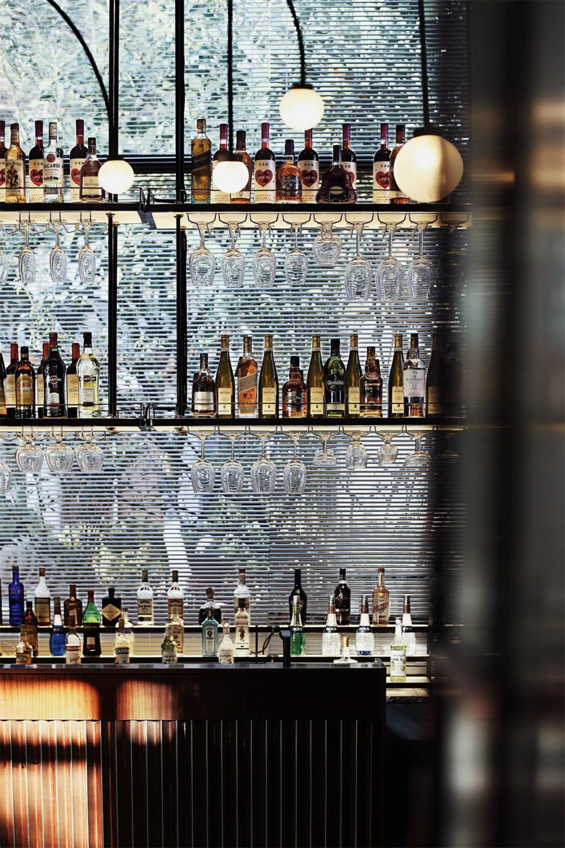 現代酒吧室內展示各式酒瓶與懸掛的玻璃杯。