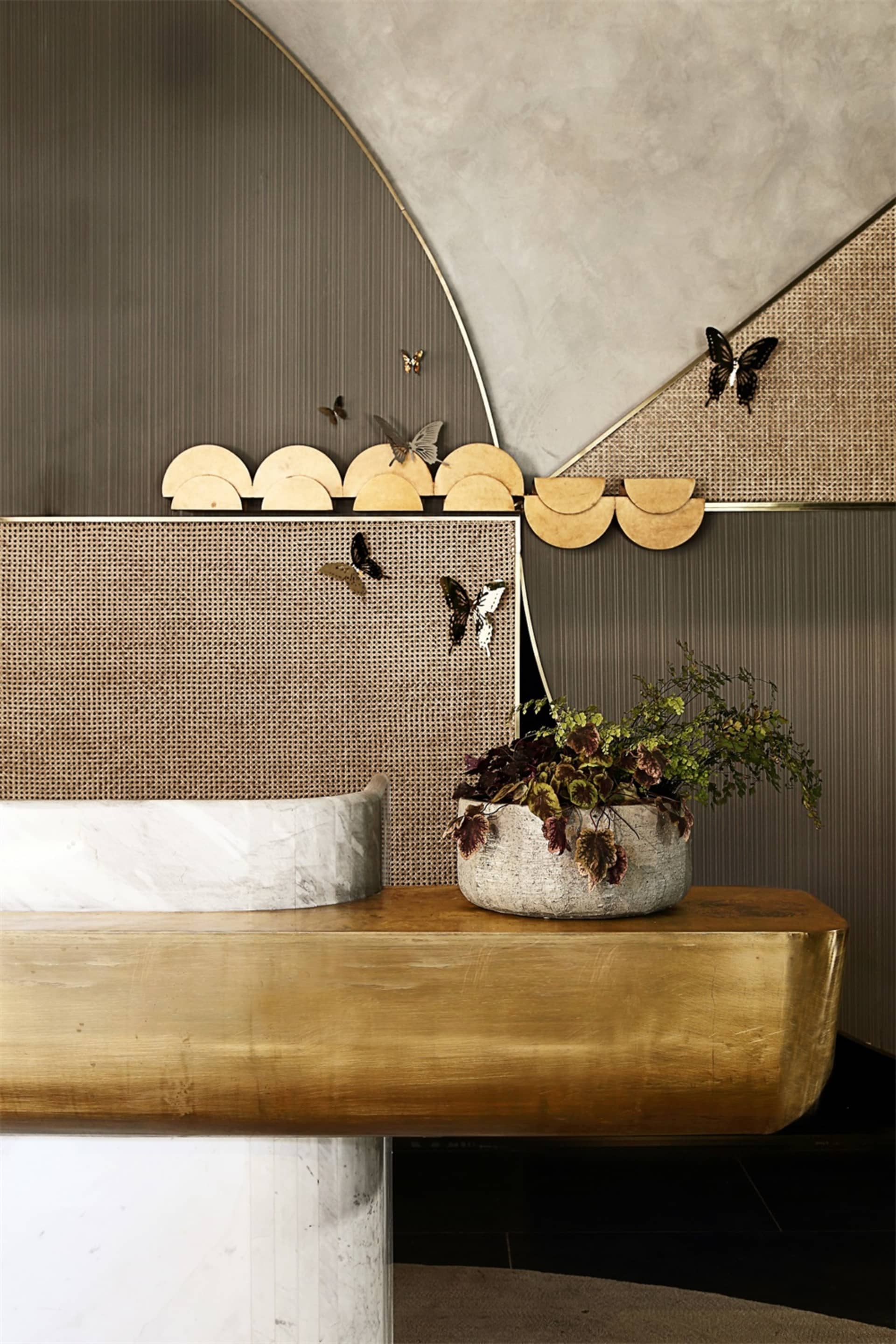 A sleek and stylish entryway with a gold leather bench, metal accents, and a potted plant.