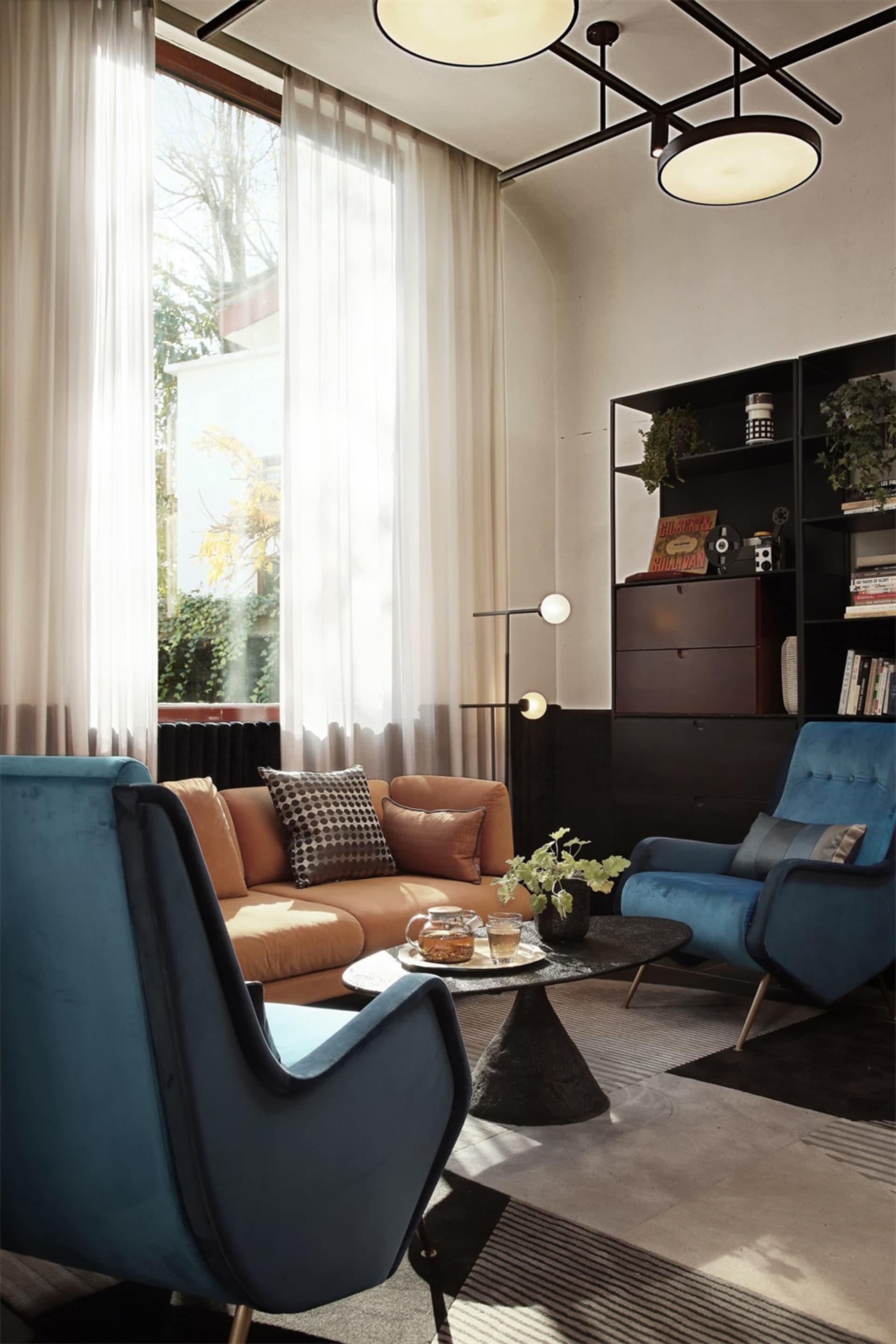 A modern living room with a mix of blue and brown furniture, including a blue armchair and a brown sofa, positioned around a